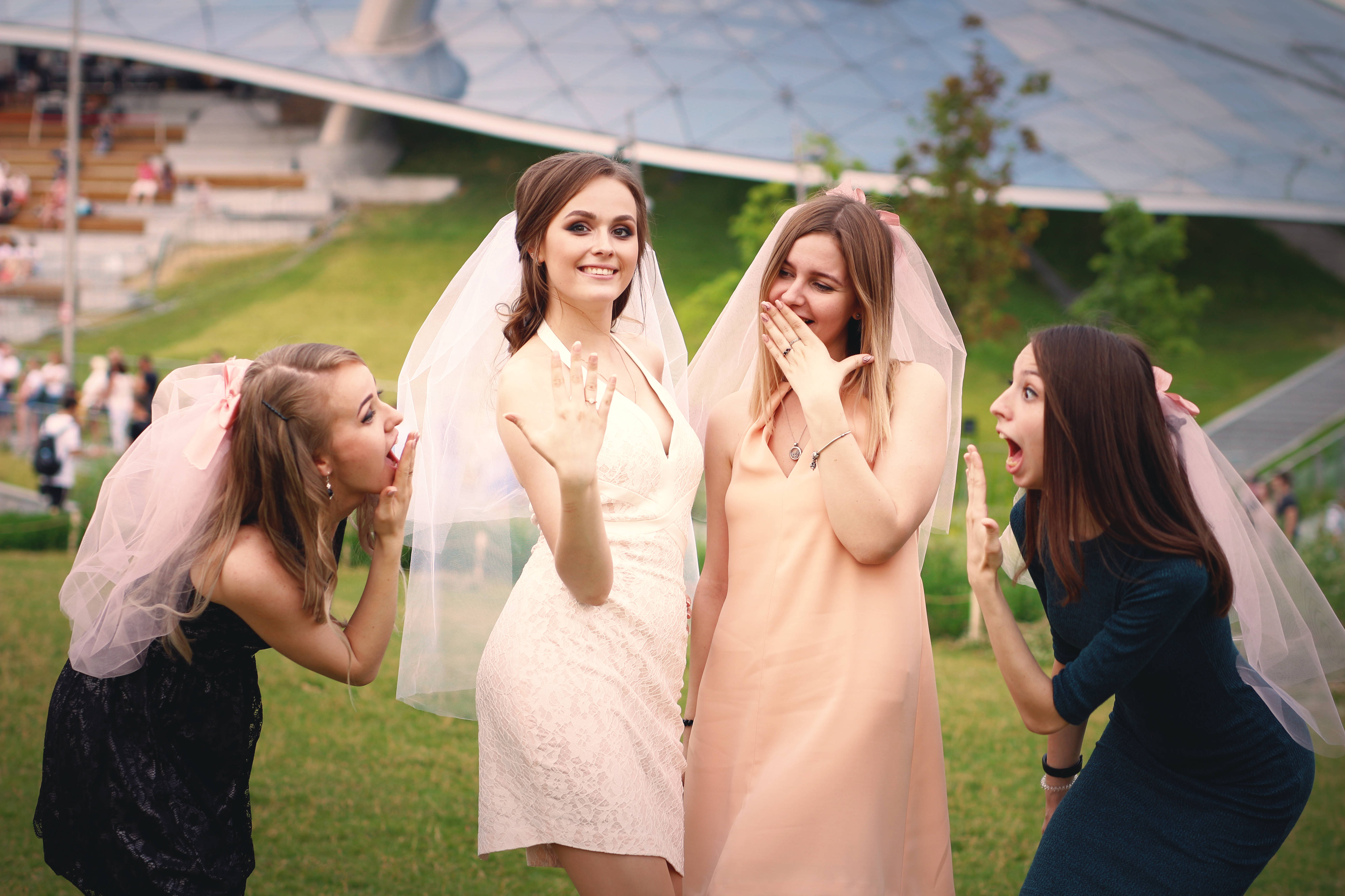 Bachelorette 桌布 壁紙 — 四位戴著頭紗的快樂伴娘，圍繞著一位穿著白色婚紗微笑的新娘，表現出驚喜和喜悅。
