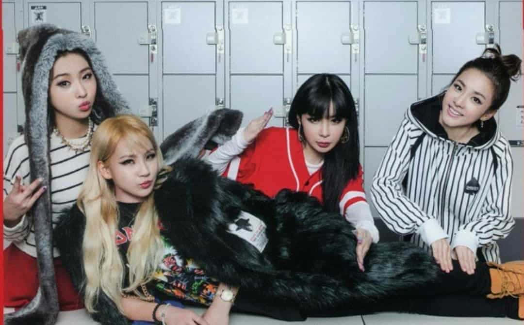 2NE1 桌布 壁紙 — 四位時尚女性在學校更衣室與一個大型黑色毛絨吉祥物頑皮地擺姿勢。