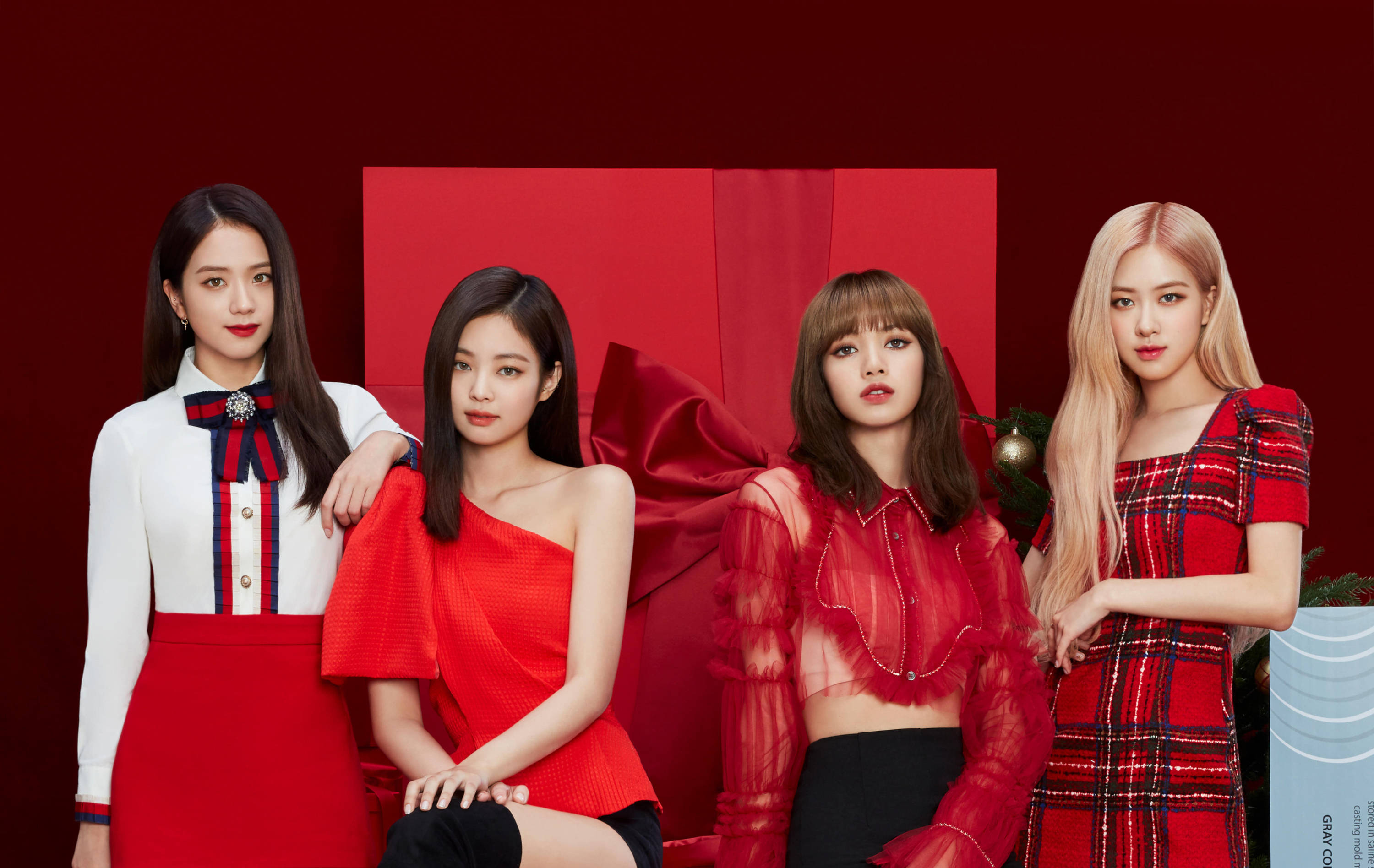 BLACKPINK 桌布 壁紙 — 四位時尚女性身穿節日紅色服裝，在帶有節日裝飾的醒目紅色背景前自信地擺姿勢。