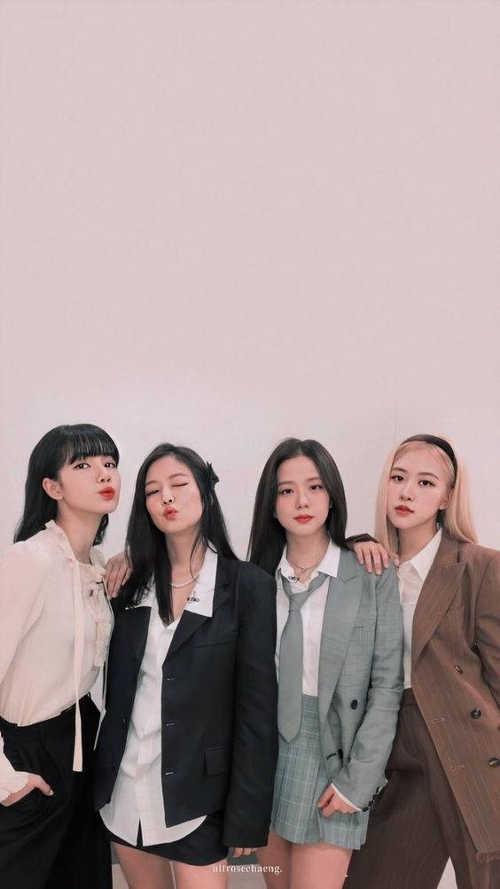 BLACKPINK 桌布 壁紙 — 四位時尚女性身穿西裝外套和別緻服裝，在柔和的粉紅色背景前自信地擺出俏皮的表情。