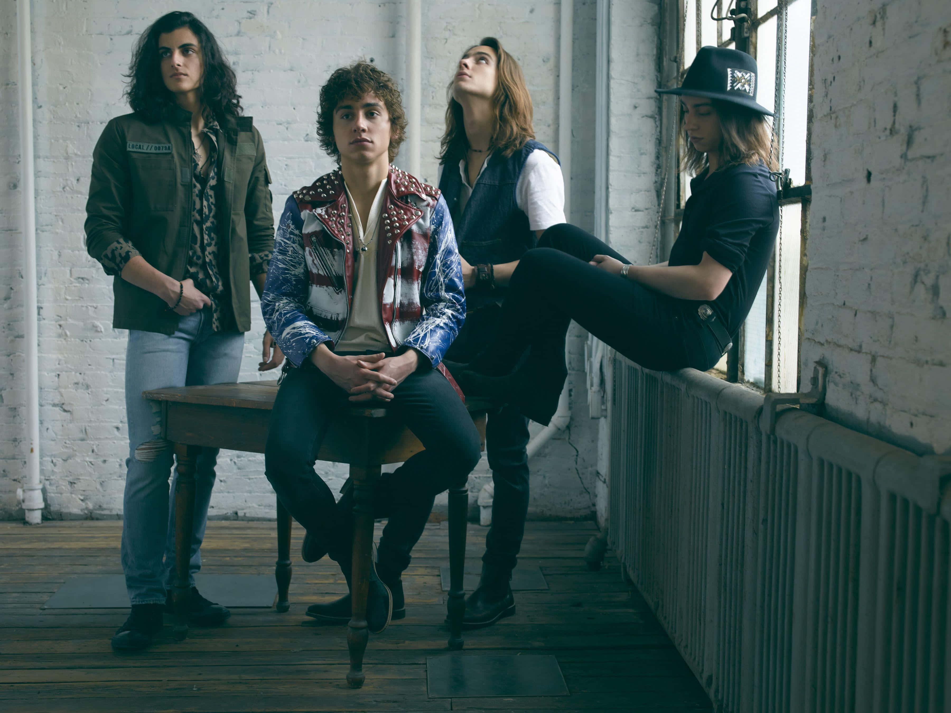 band 桌布 壁紙 — 四位時尚年輕人在一個帶有白色磚牆和木地板的鄉村工業風閣樓中隨意擺姿勢。