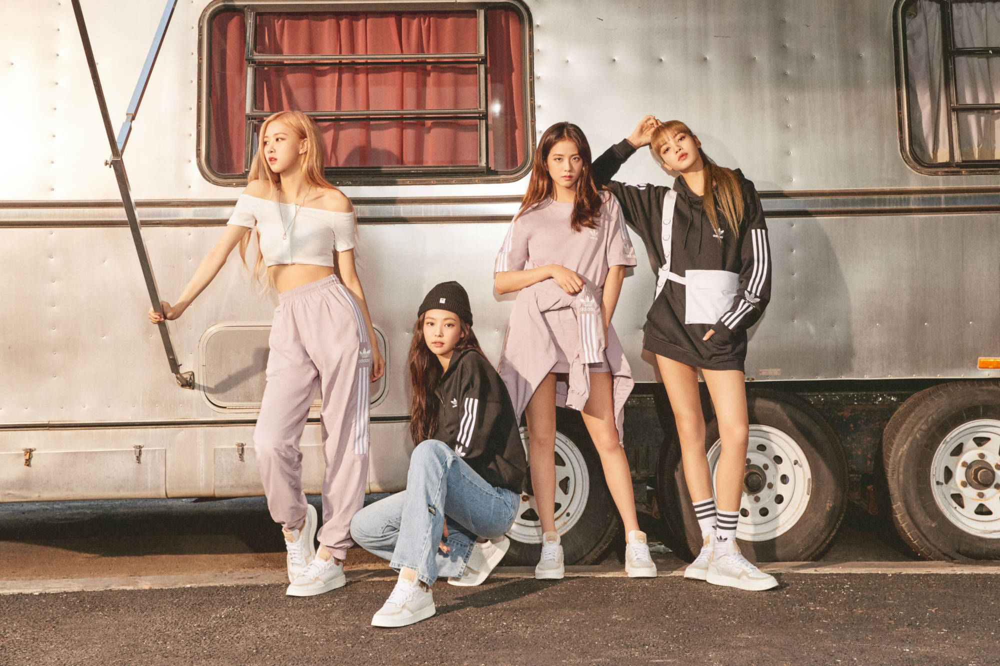 BLACKPINK 桌布 壁紙 — 四位時尚年輕女性穿著運動服，自信地在帶有紅色窗簾的復古銀色露營車前擺姿勢。