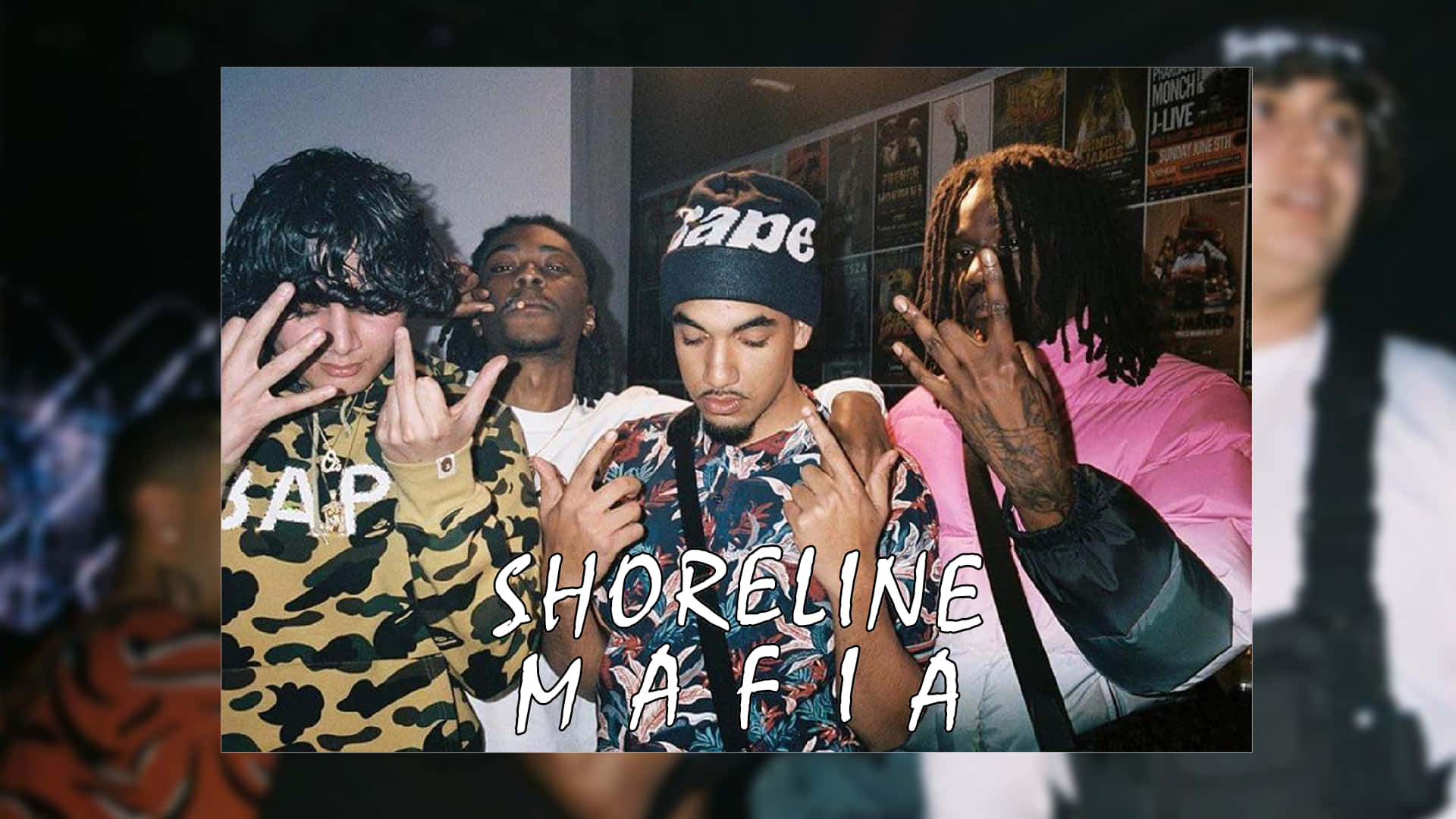 Shoreline Mafia 桌布 壁紙 — 四位時尚年輕男子在燈光昏暗、牆上貼有海報的房間內自信擺姿勢，並做出手勢。