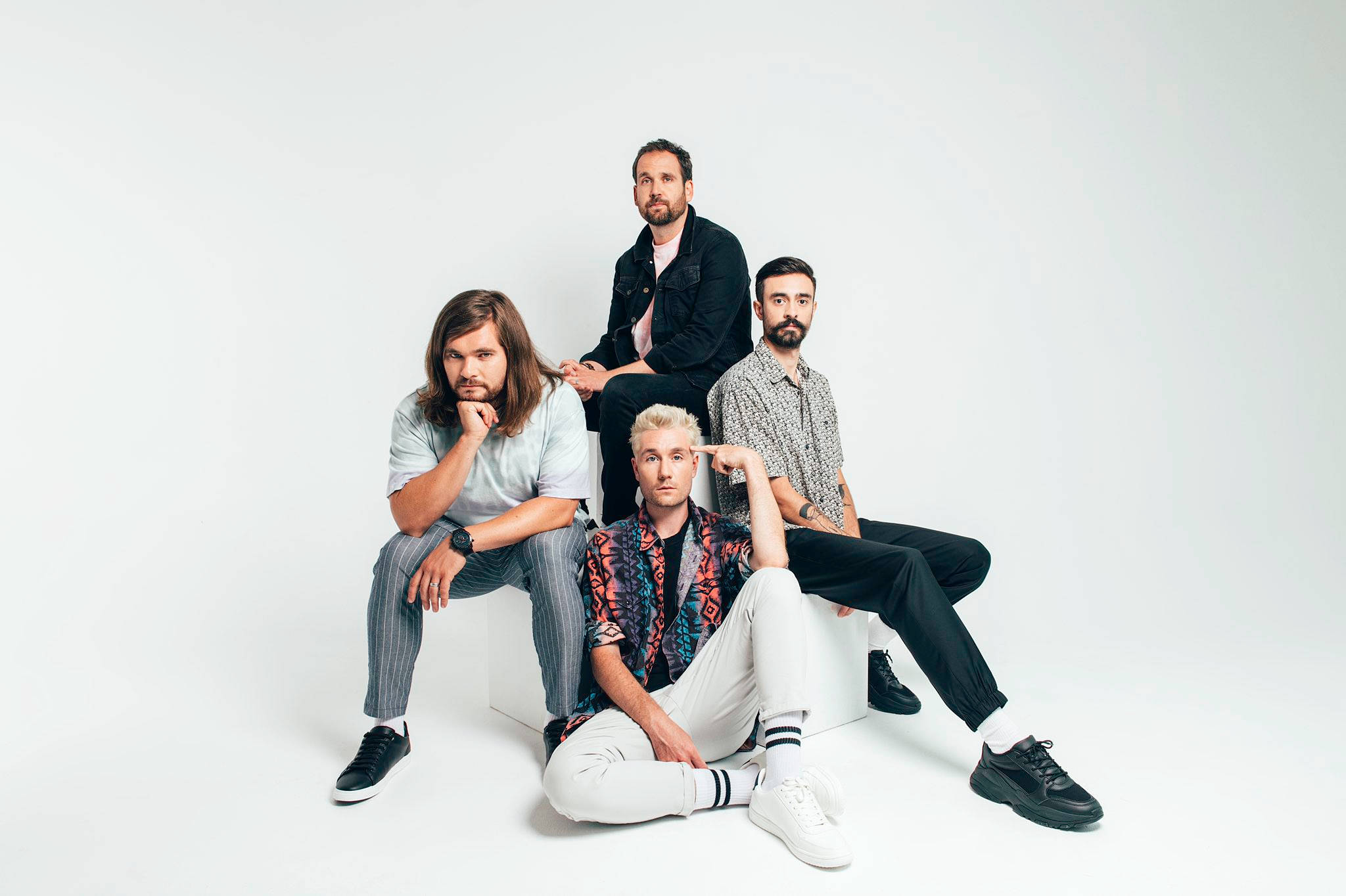 Bastille 桌布 壁紙 — 四位時尚男士自信地站在白色方塊上，背景是無縫的白色攝影棚。