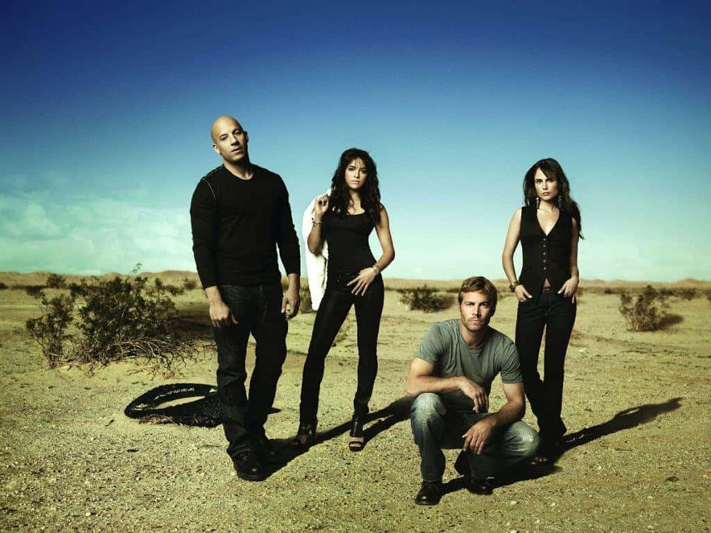 Fast And Furious 桌布 壁紙 — 四位演員在陽光明媚的沙漠中自信地擺姿勢，沙漠中有稀疏的灌木和清澈的藍天。