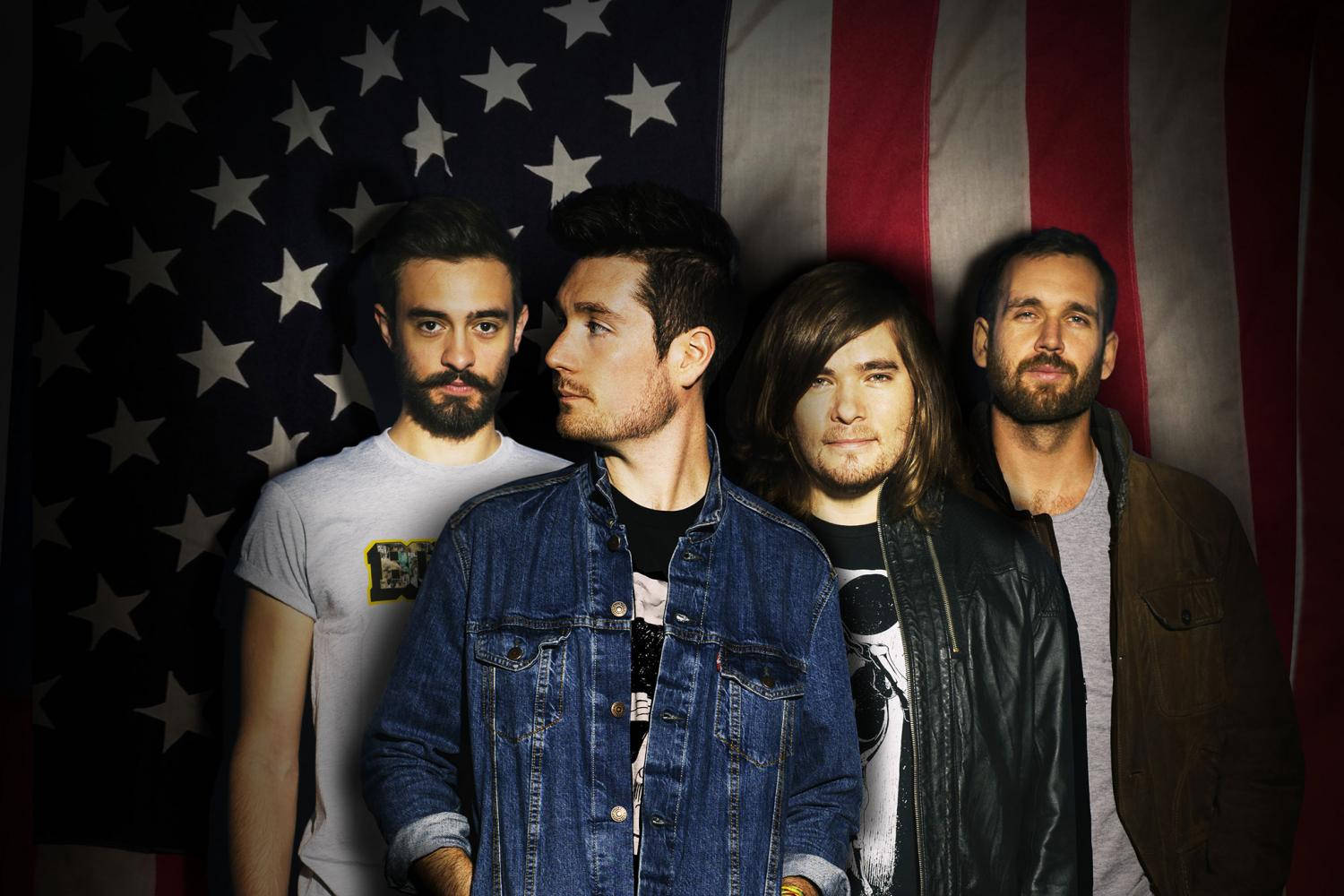 Bastille 桌布 壁紙 — 四位留鬍鬚、穿著休閒服裝的男士自信地站在工作室內的大型美國國旗背景前。