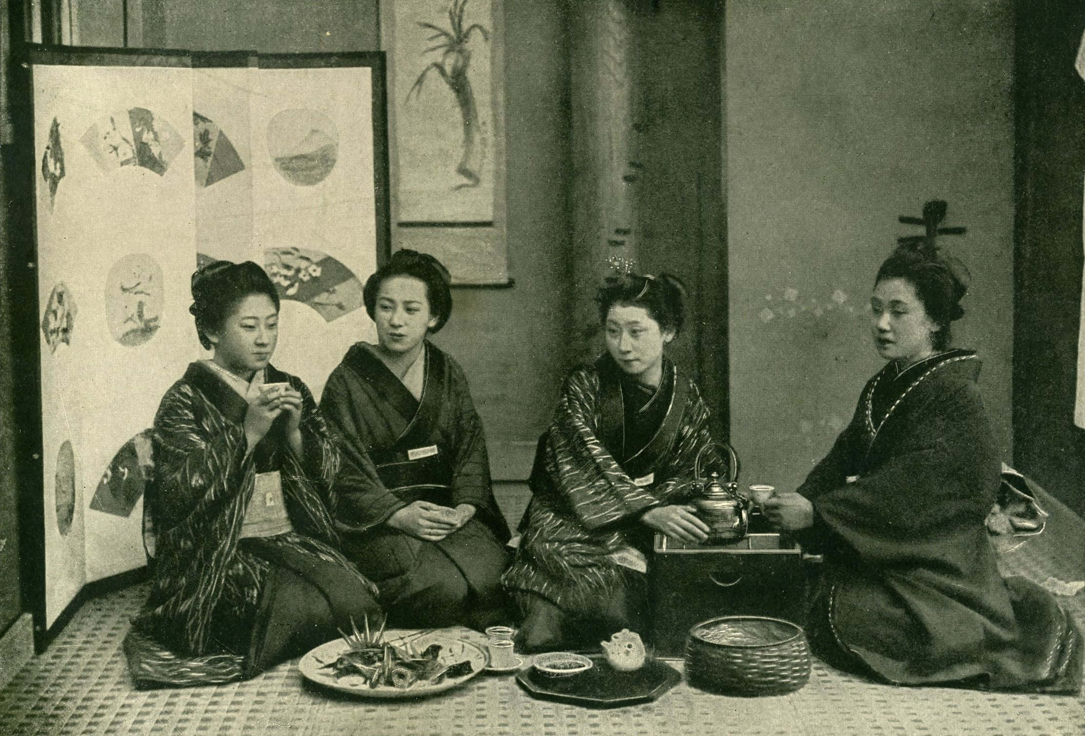 日式 桌布 壁紙 — 四位穿著傳統和服的女性坐在日式房間的榻榻米上，在安靜的文化聚會中分享茶和小吃。