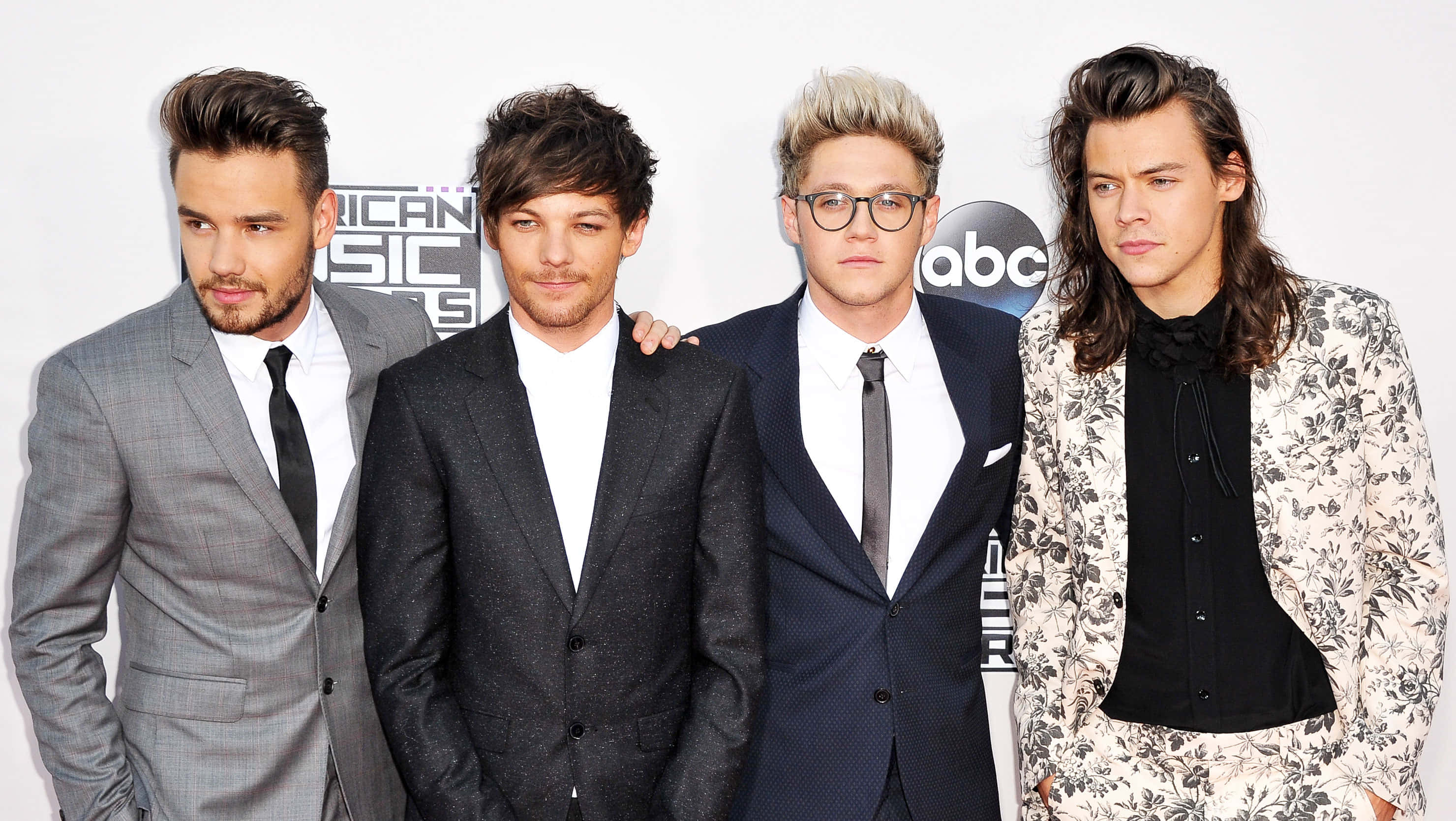 One Direction 桌布 壁紙 — 四位穿著正式西裝的時尚男士在『美國音樂獎』背景的紅地毯活動中自信地擺姿勢。