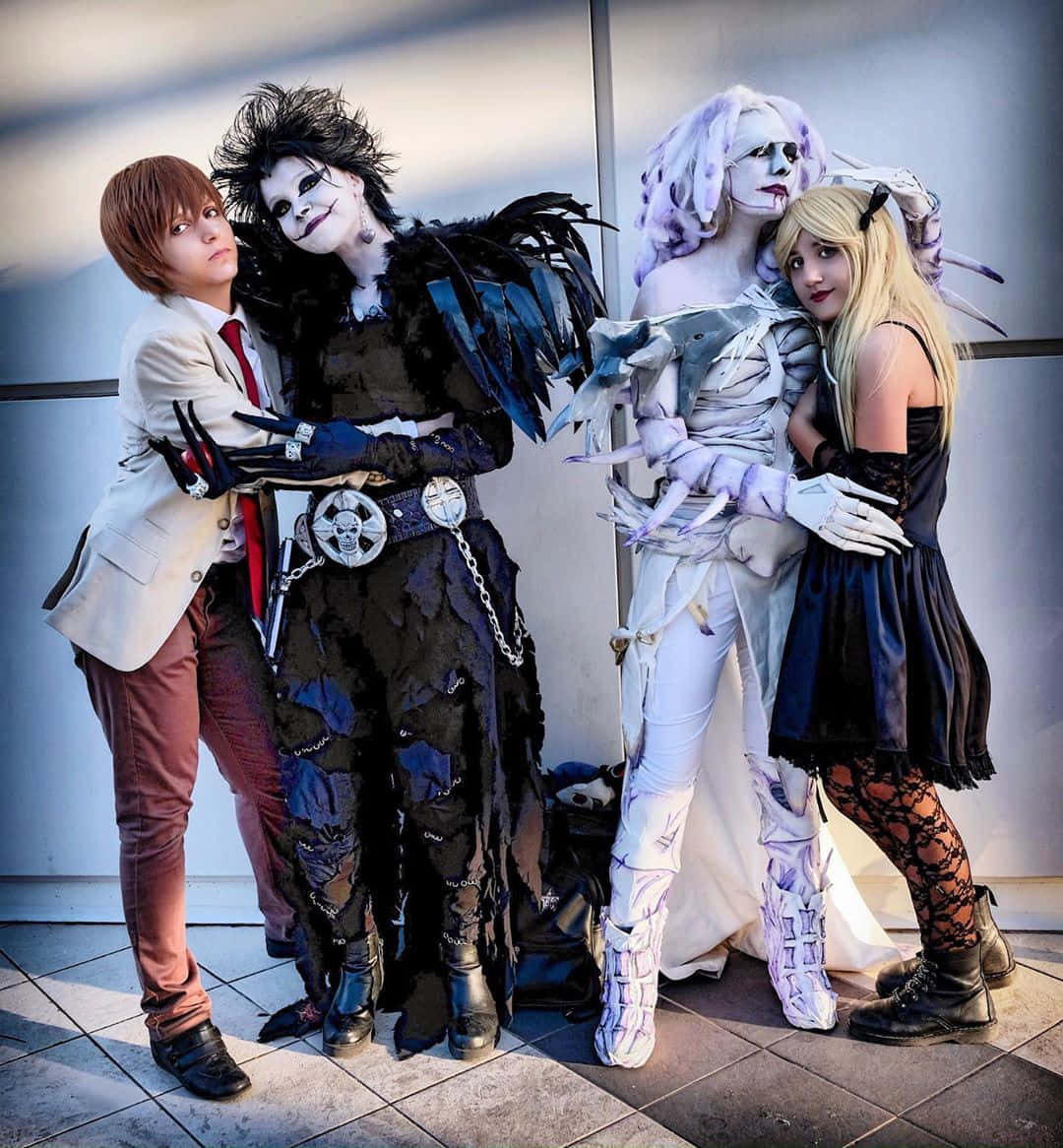 Death Note Rem 桌布 壁紙 — 四位穿著精緻暗黑奇幻服裝的角色扮演者，在磁磚地板上靠著素牆一起擺姿勢。