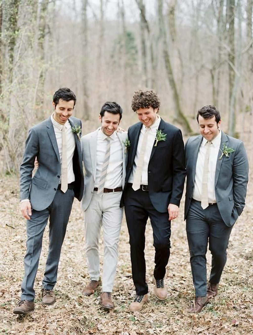 Groomsmen 桌布 壁紙 — 四位穿著訂製西裝和襟花的伴郎，一邊走過落葉滿地的森林，一邊開懷大笑。