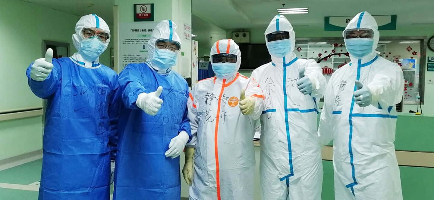 四位穿著防護衣的人站在醫院裡 壁紙