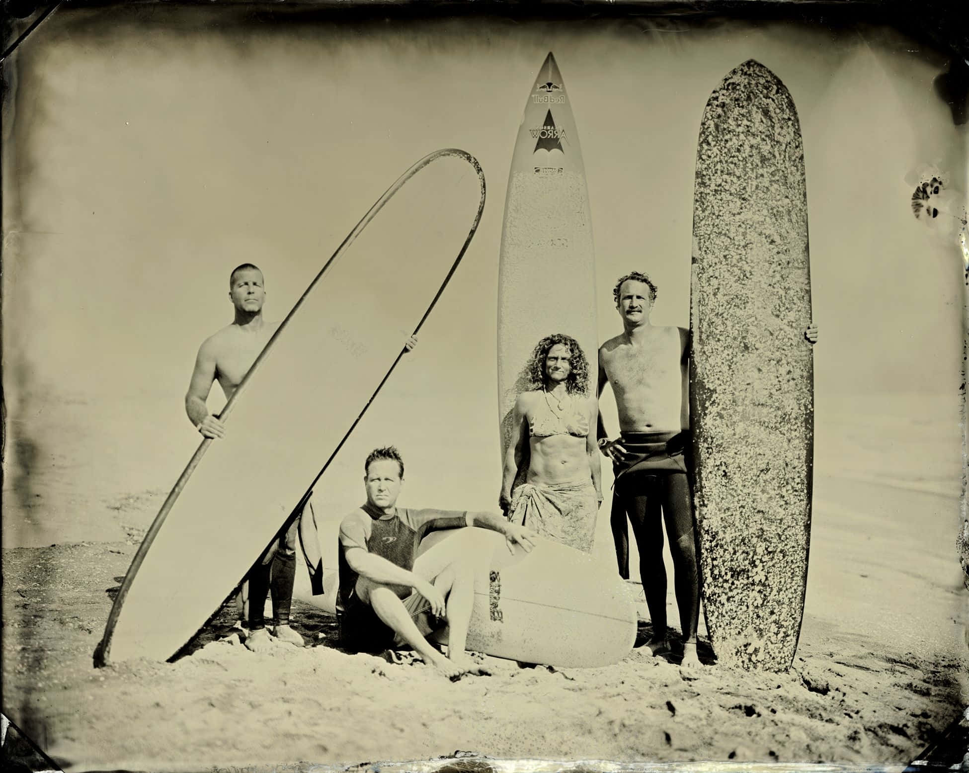 surfing 桌布 壁紙 — 四位衝浪者拿著復古衝浪板，在陽光普照的海灘上擺姿勢，呈現復古風格的棕褐色照片。