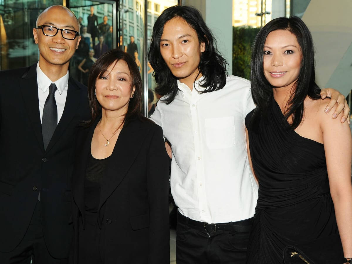 Alexander Wang 桌布 壁紙 — 四位衣著優雅的人士在現代玻璃牆的城市環境中，搭配溫暖的燈光一起擺姿勢。