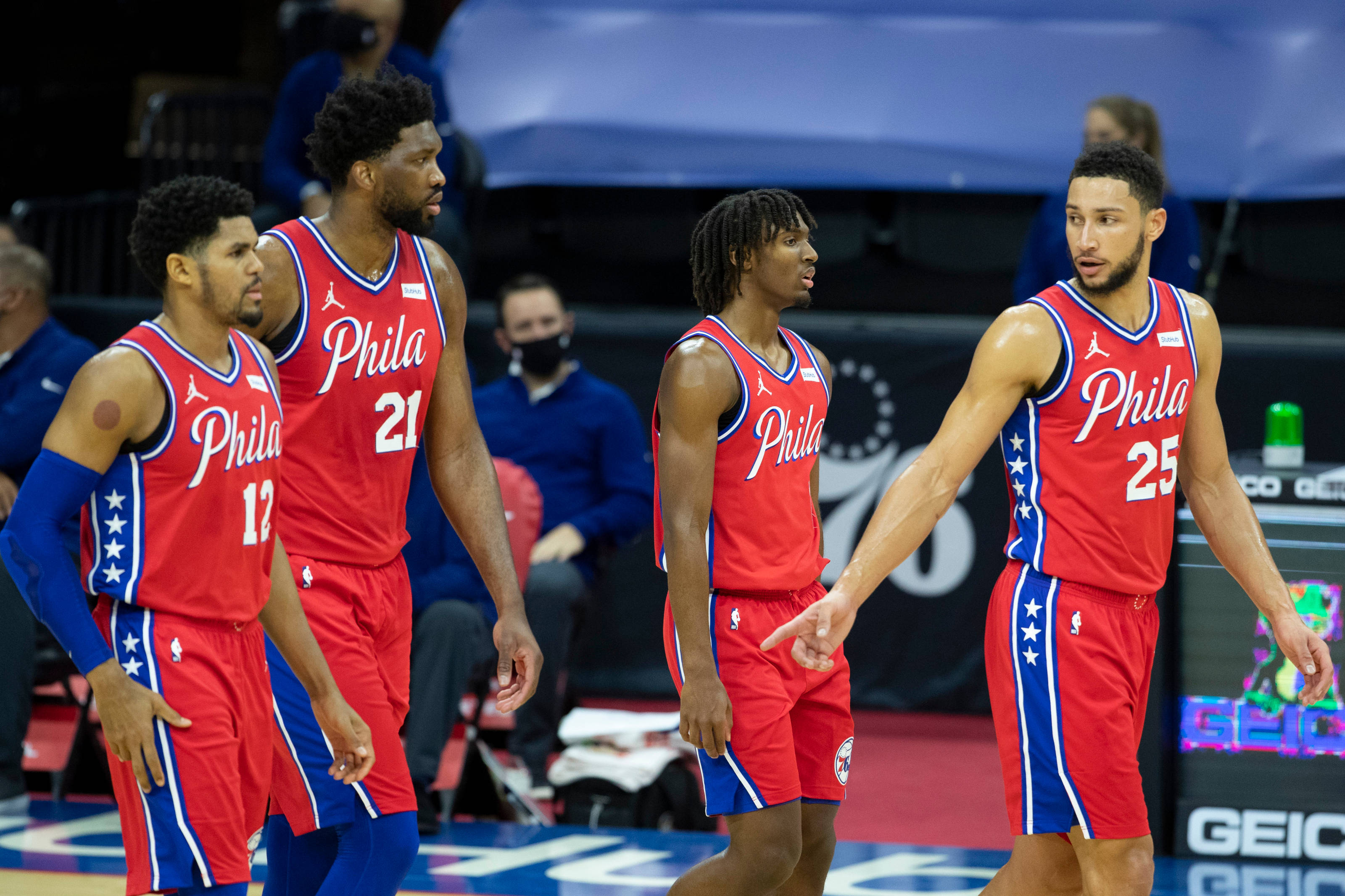 76ers 桌布 壁紙 — 四位費城76人籃球運動員身穿紅藍球衣，在比賽中站在球場上，神情專注投入。