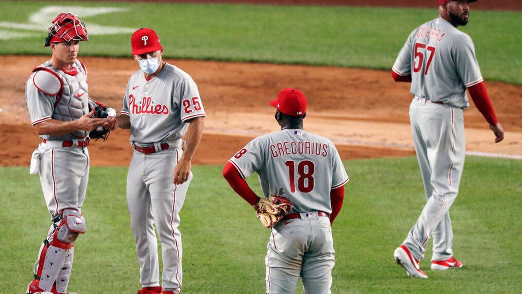 Phillies 桌布 壁紙 — 四位費城費城人棒球選手身穿灰色球衣，在球場燈光下的綠色場地上互動。