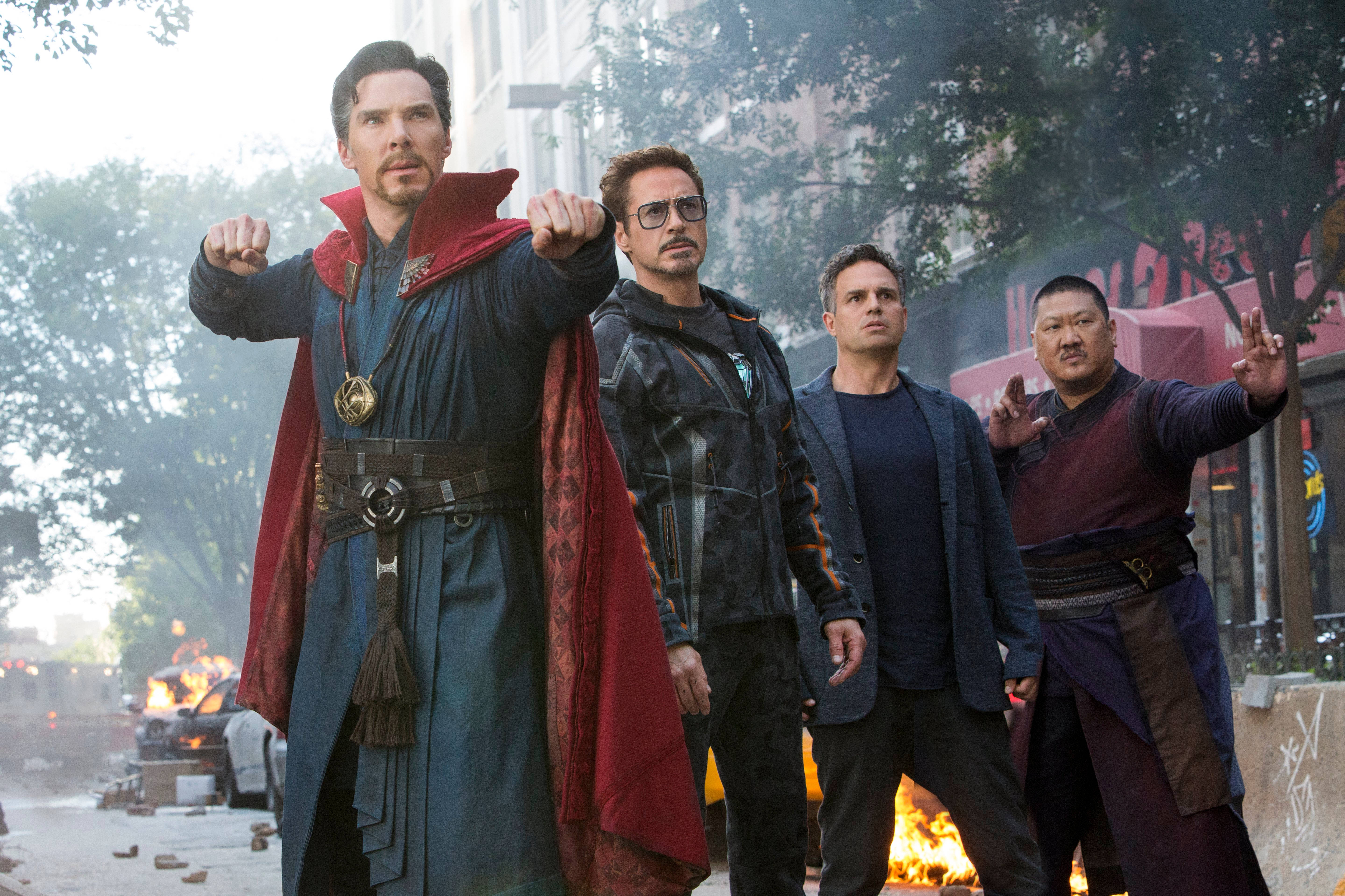 infinity 桌布 壁紙 — 四位超級英雄堅定地站在煙霧瀰漫的城市街道上，身後火焰在都市混亂中爆發。