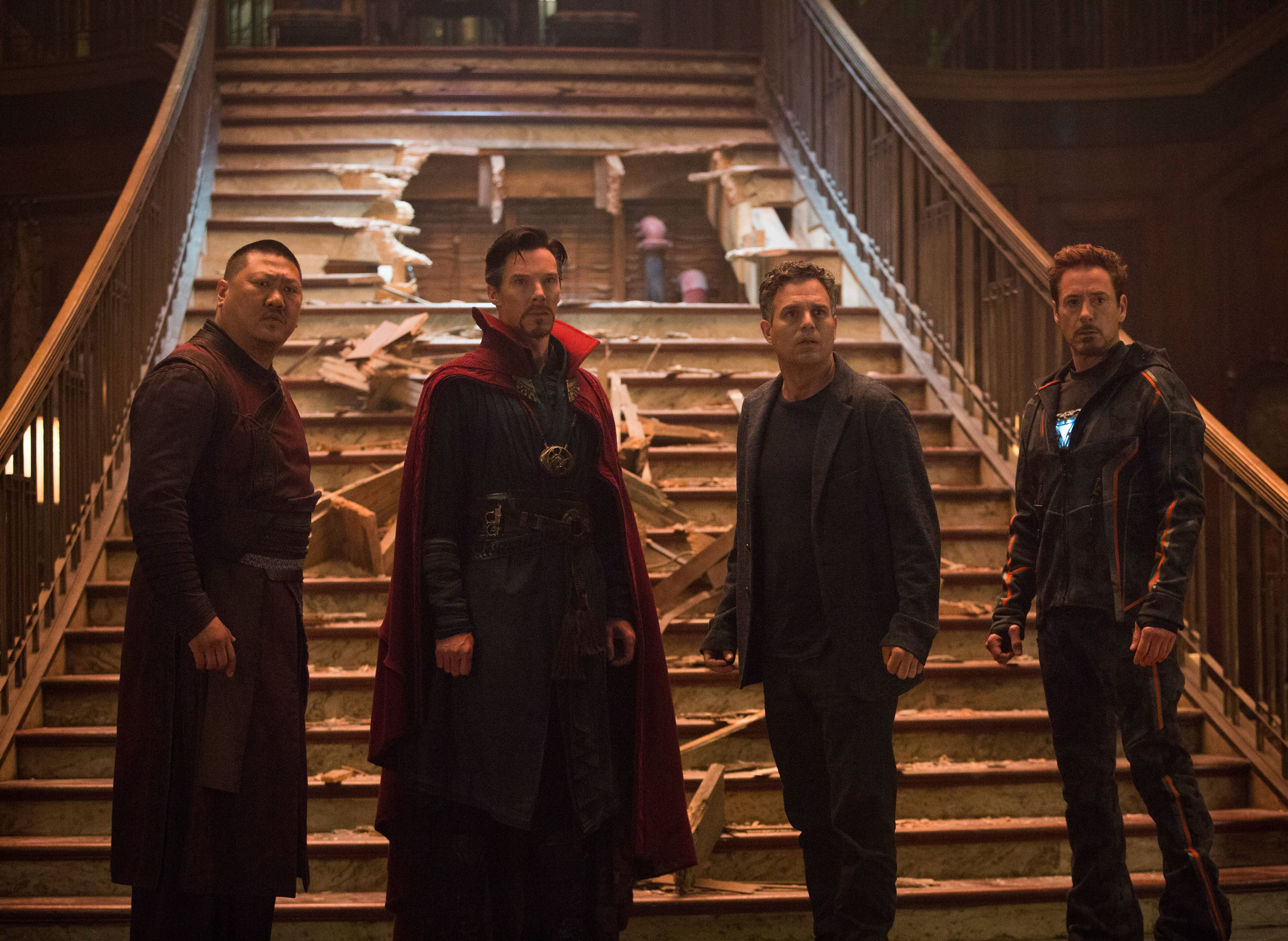 infinity 桌布 壁紙 — 四位超級英雄莊嚴地站在一個光線昏暗、飽經戰火摧殘的室內空間中，一座損壞的木樓梯底部。