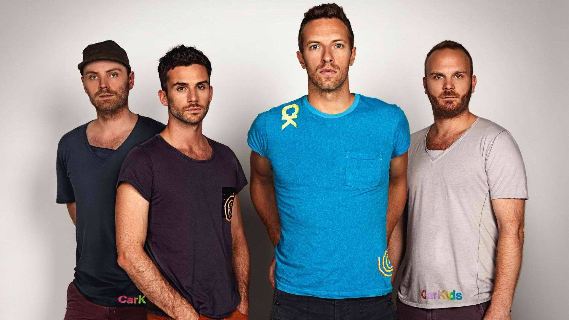 Chris Martin 桌布 壁紙 — 四位身穿休閒T恤的男子在純白色攝影棚背景前嚴肅地擺姿勢。