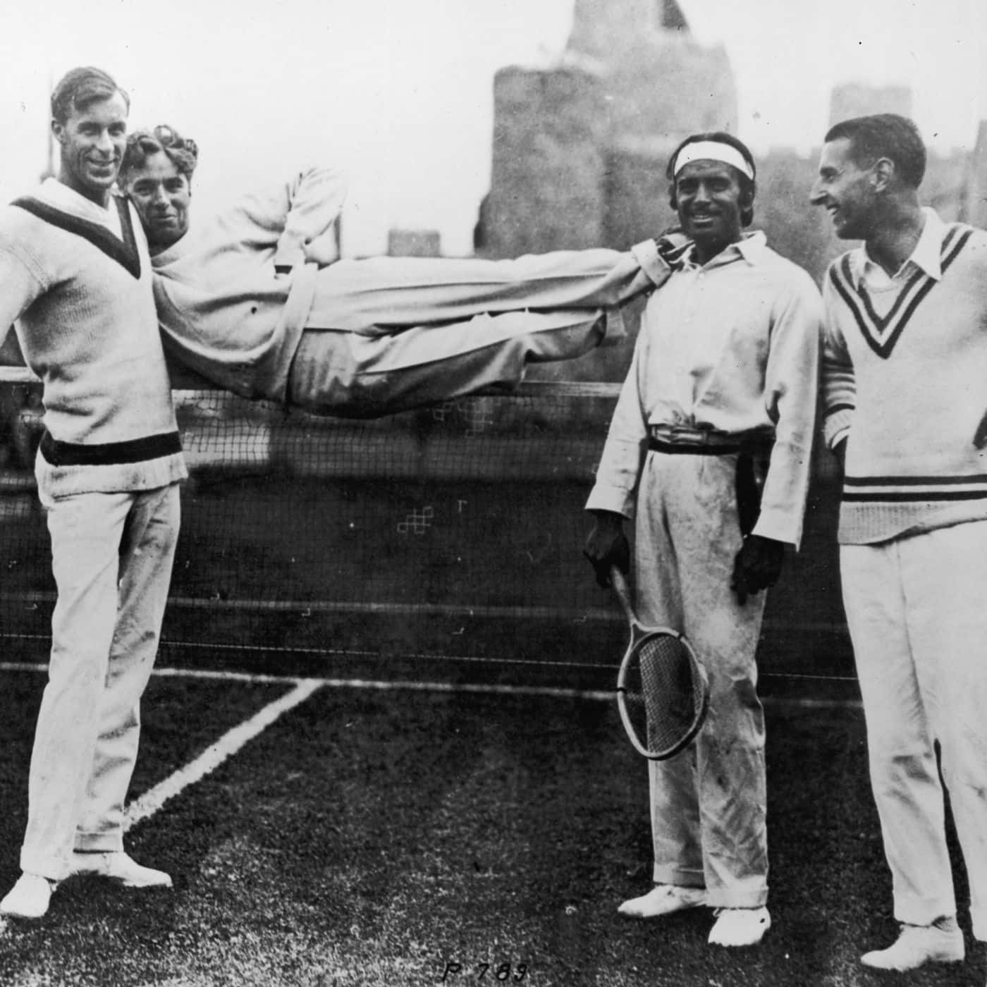 Tennis 桌布 壁紙 — 四位身穿復古網球服裝的男子在球場上愉快地擺姿勢，其中一人拿著球拍，另一人被頑皮地舉過網。