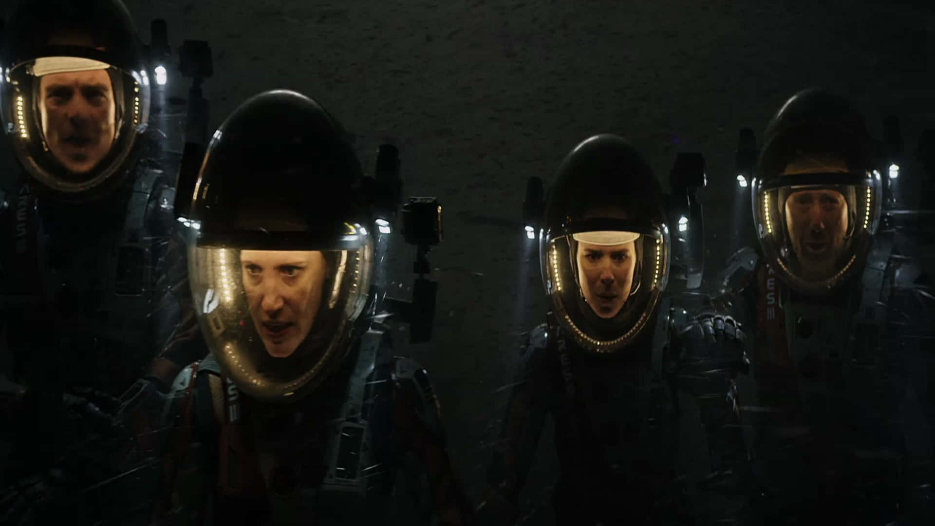 The Martian 桌布 壁紙 — 四位身穿深色太空衣、頭盔燈發光的太空人在昏暗的太空站走廊中專注地凝視。