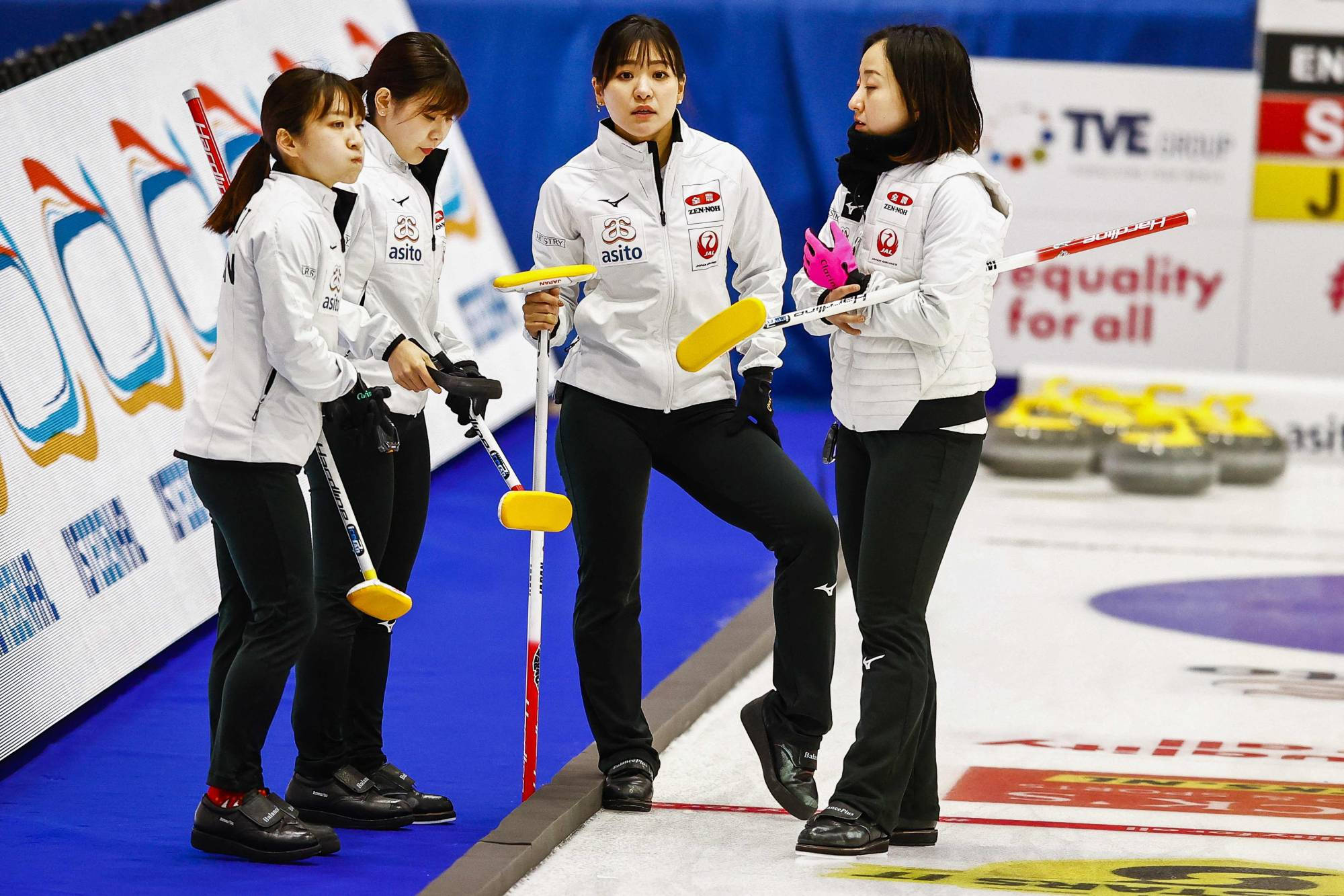 Olympics 桌布 壁紙 — 四位身穿白色制服的女冰壺運動員在冰場上拿著黃色冰壺掃帚激烈地制定策略。