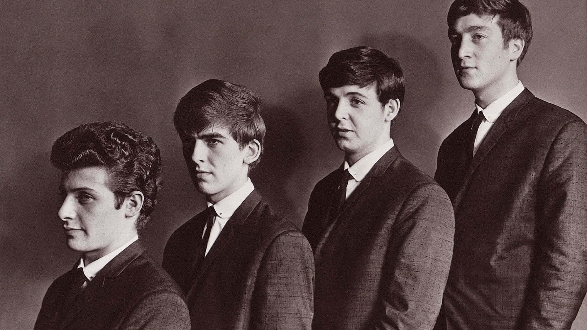 the beatles 桌布 壁紙 — 四位身穿西裝的年輕男子在樸素的工作室背景前莊嚴地擺姿勢，呈現復古黑白肖像。