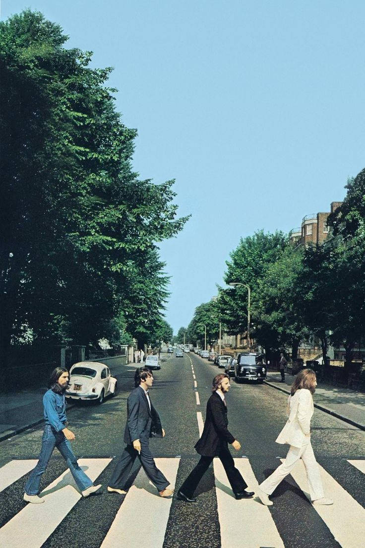 the beatles 桌布 壁紙 — 四位身穿西裝的男士在晴朗藍天下，穿過兩旁種滿翠綠樹木和停有復古汽車的斑馬線。