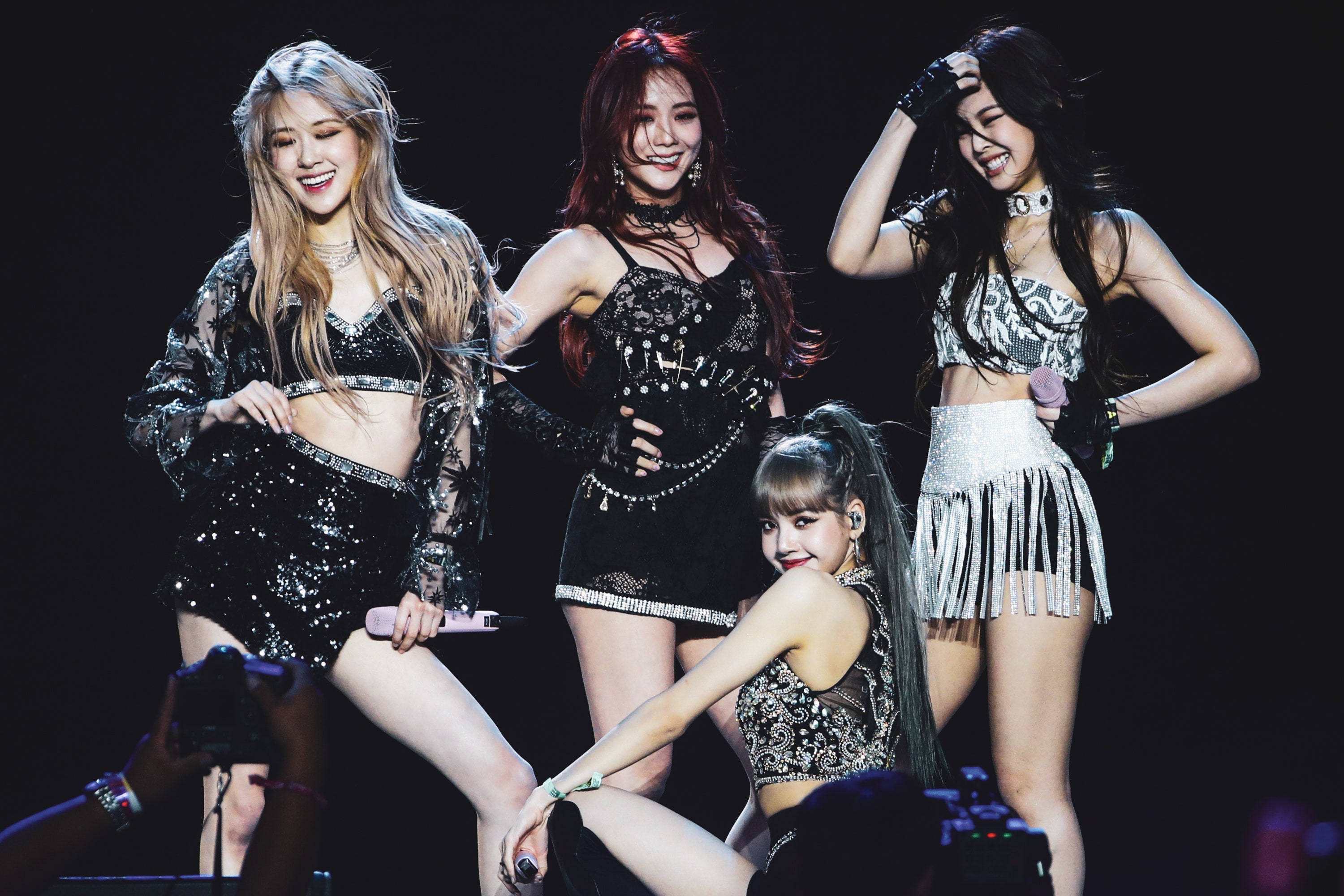 BLACKPINK 桌布 壁紙 — 四位身穿閃亮黑色和銀色服裝的K-pop女偶像在明亮的舞台燈光下擺出動態姿勢。