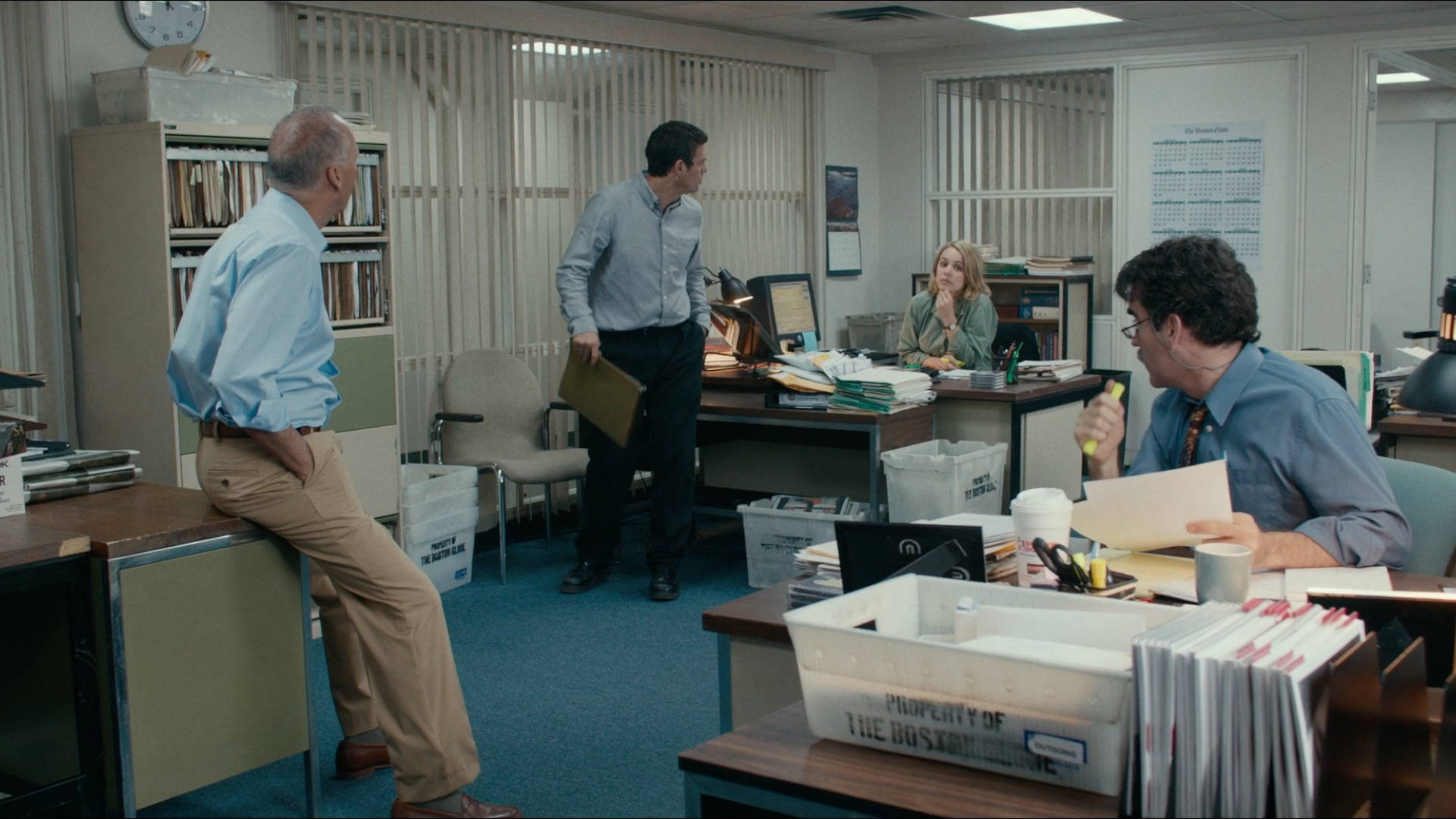 Spotlight 桌布 壁紙 — 四位辦公室員工在雜亂的1980年代辦公室中，在成堆的文件和復古家具間交談。