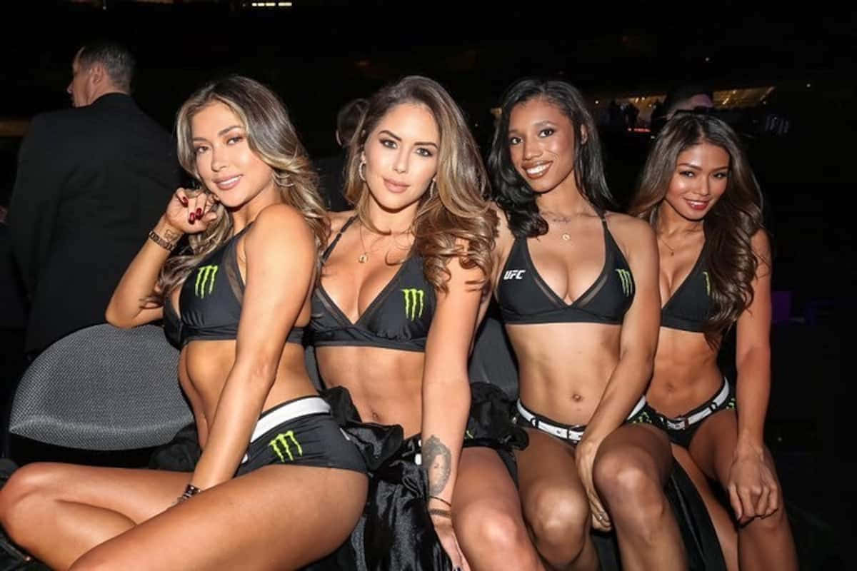 Hot Girls And Sexy Photos 桌布 壁紙 — 四位面帶微笑的女性穿著黑色和綠色的Monster Energy UFC品牌服裝，在燈光昏暗的活動中一起擺姿勢。