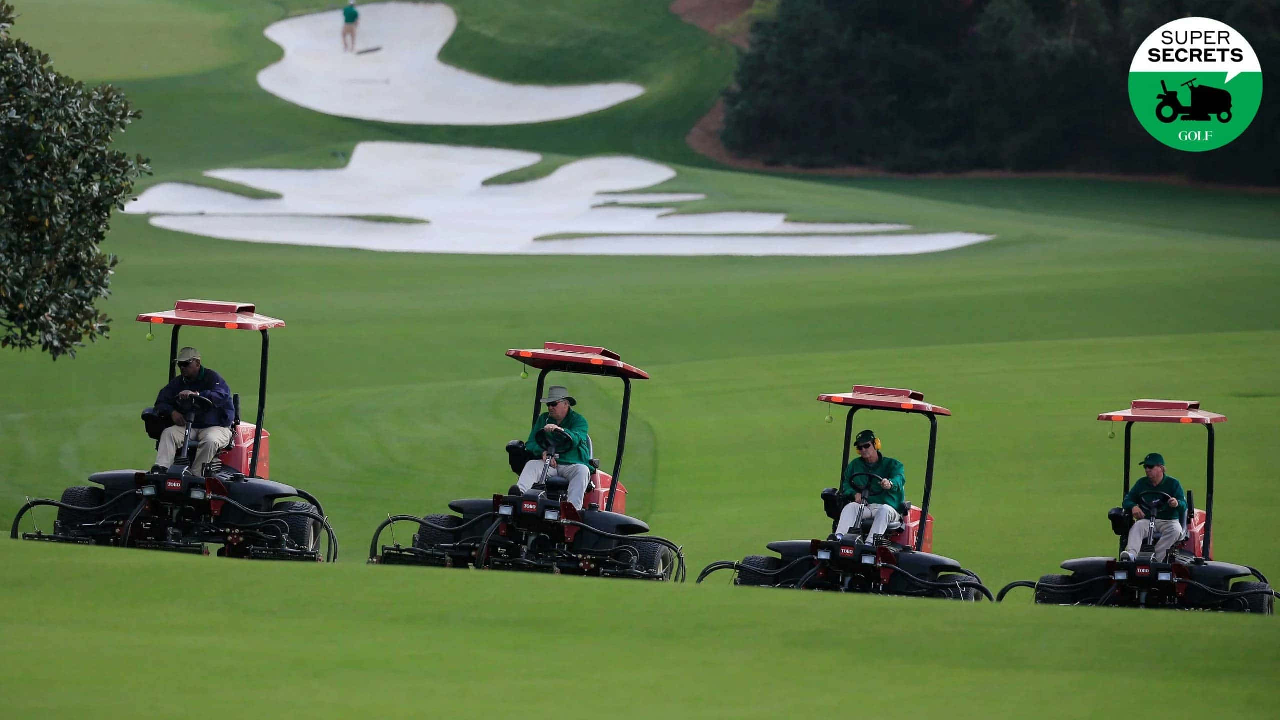 Augusta National iPhone 桌布 壁紙 — 四位高爾夫球手乘坐紅色球車穿越翠綠的球道，設有沙坑和遠處果嶺上的球員。