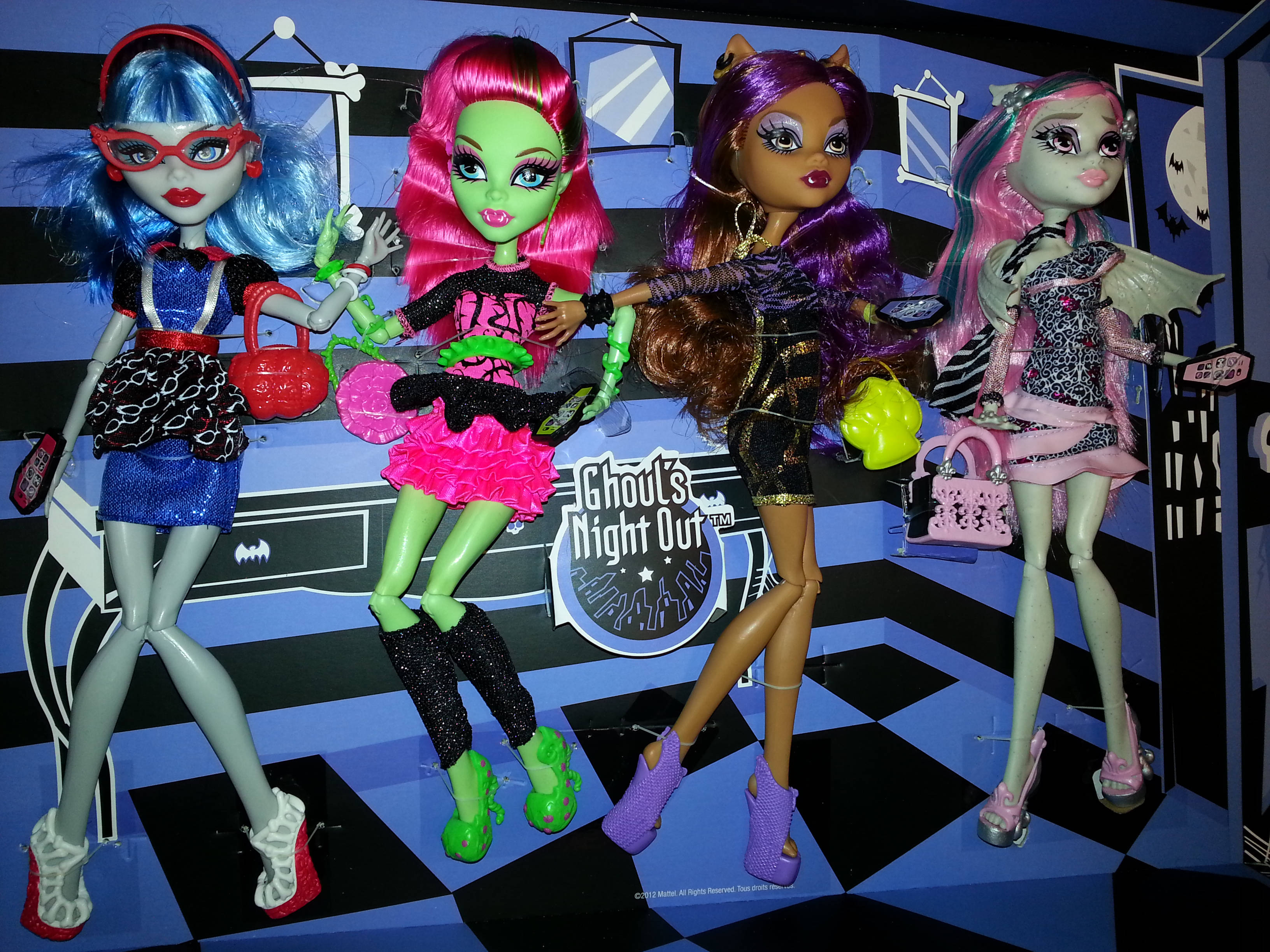 bratz 美學 桌布 壁紙 — 四個Monster High公仔在黑色和藍色格紋地板上時尚地擺姿勢，背景是恐怖主題。