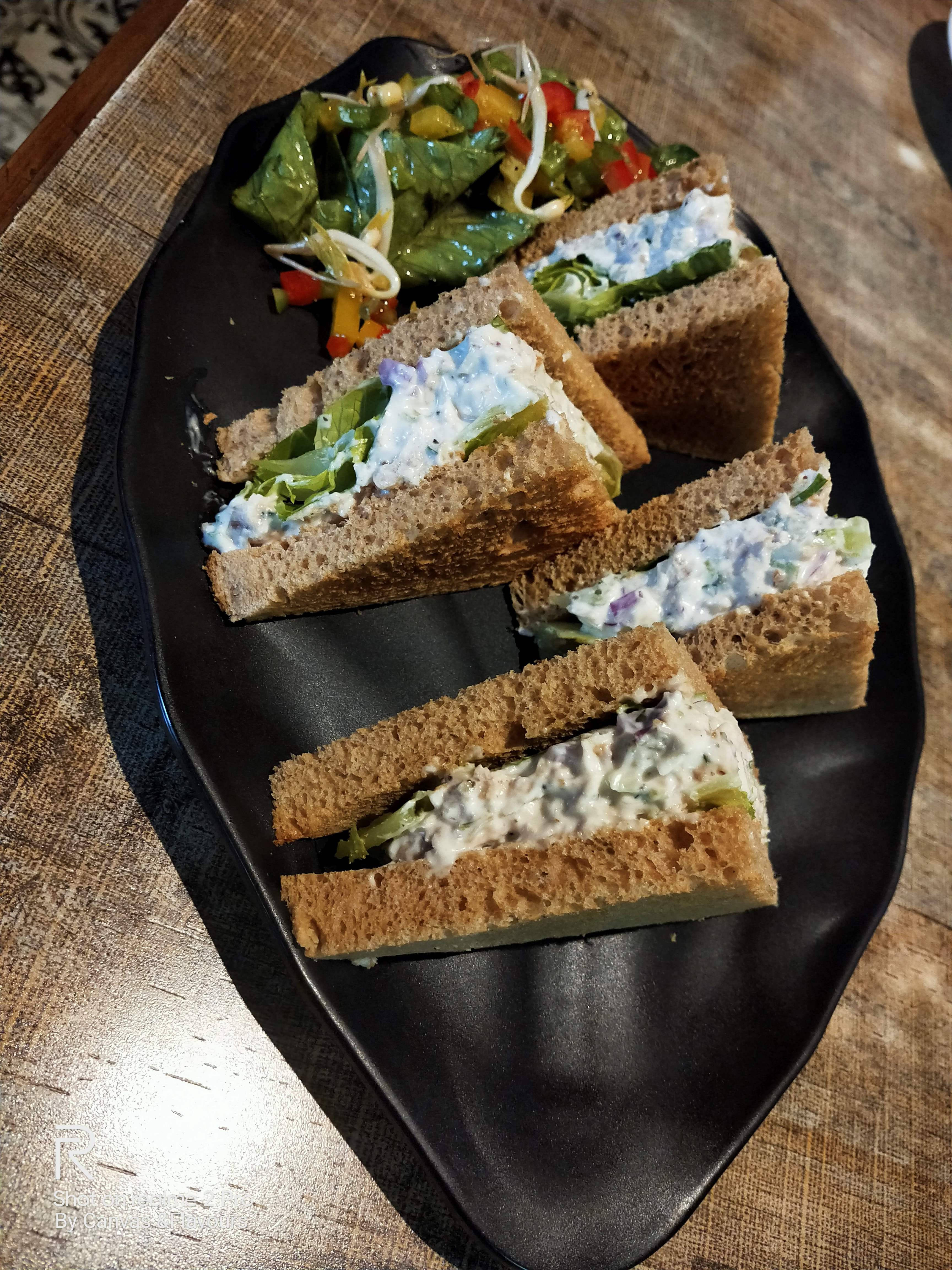 Healthy Food 桌布 壁紙 — 四個三角形全麥三明治配奶油餡料及沙拉，放在黑色葉形盤子上。