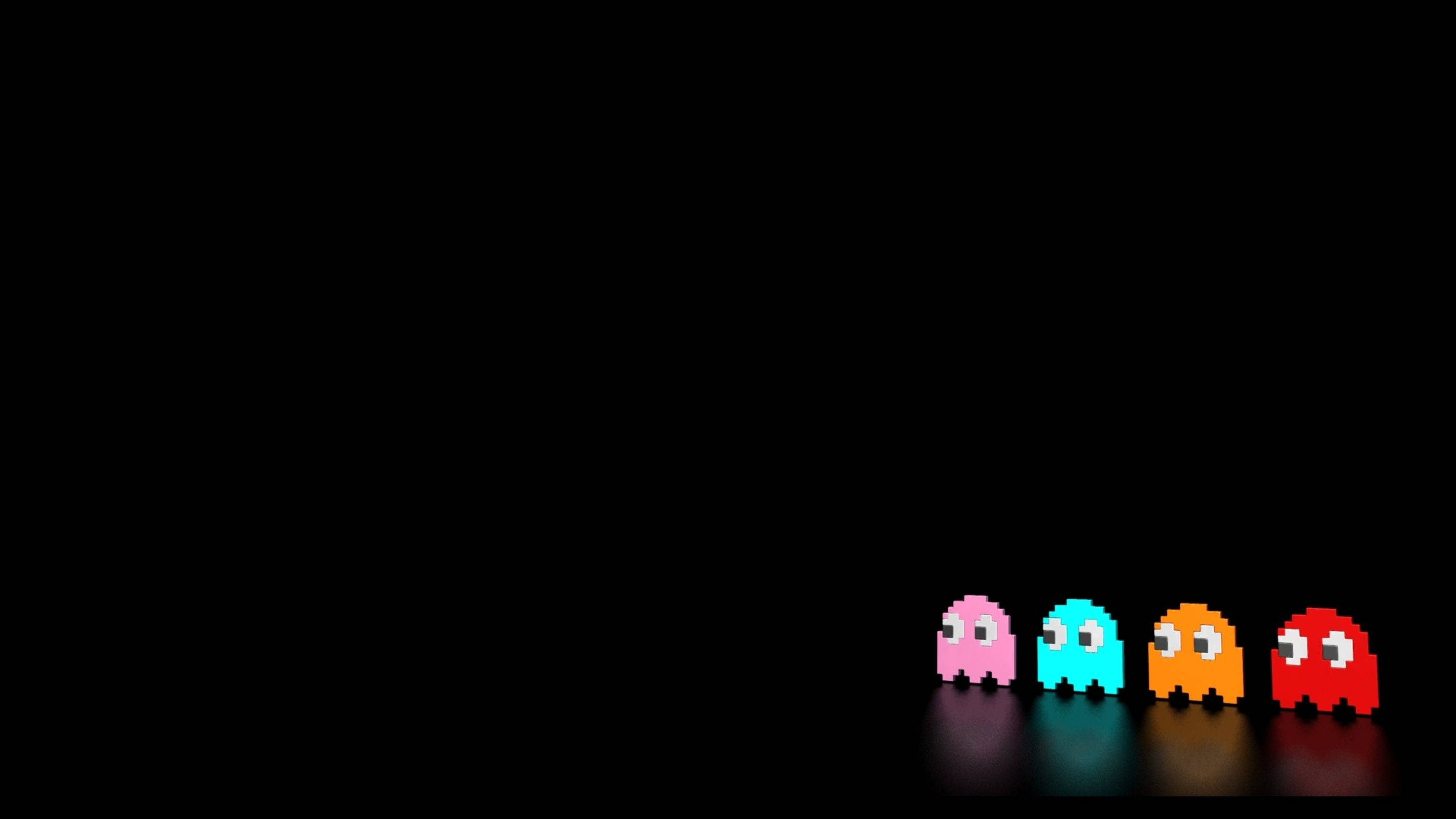 game 桌布 壁紙 — 四個像素化的 Pac-Man 鬼魂，分別為粉紅色、青色、橙色和紅色，排列在一行，背景為黑色，帶有微妙的反射。