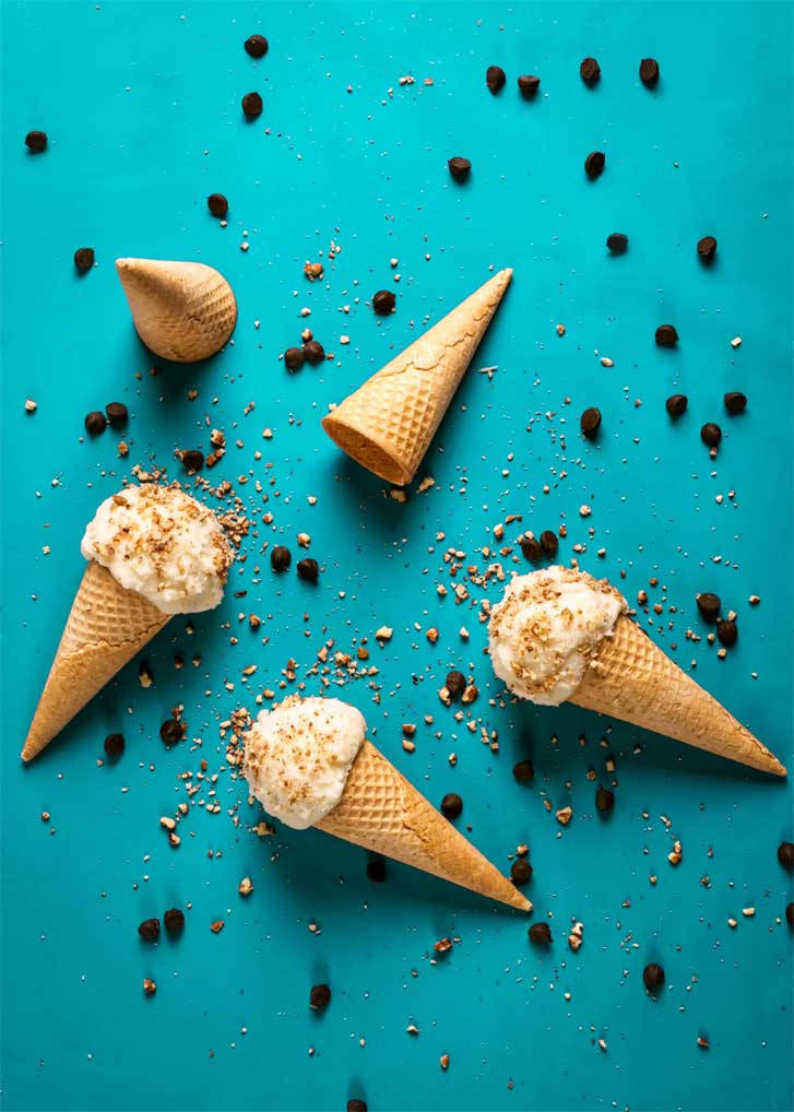 Ice Cream 桌布 壁紙 — 四個冰淇淋甜筒，上面有焦糖化配料和巧克力碎，散落在充滿活力的青綠色背景上。