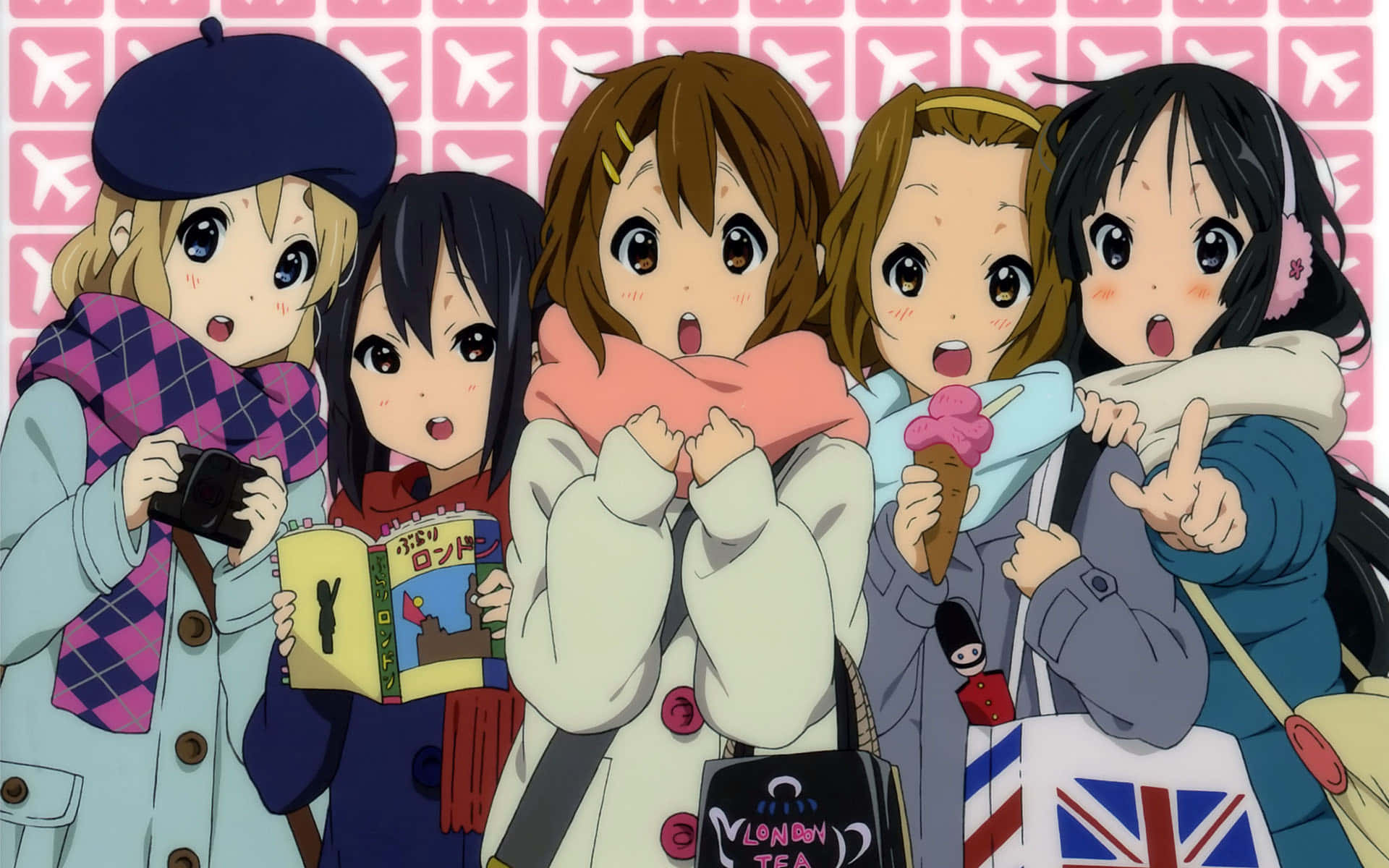 K-ON！輕音部 桌布 壁紙 — 四個動漫女孩穿著冬季外套和圍巾，在粉紅色飛機圖案背景前開心地擺姿勢。