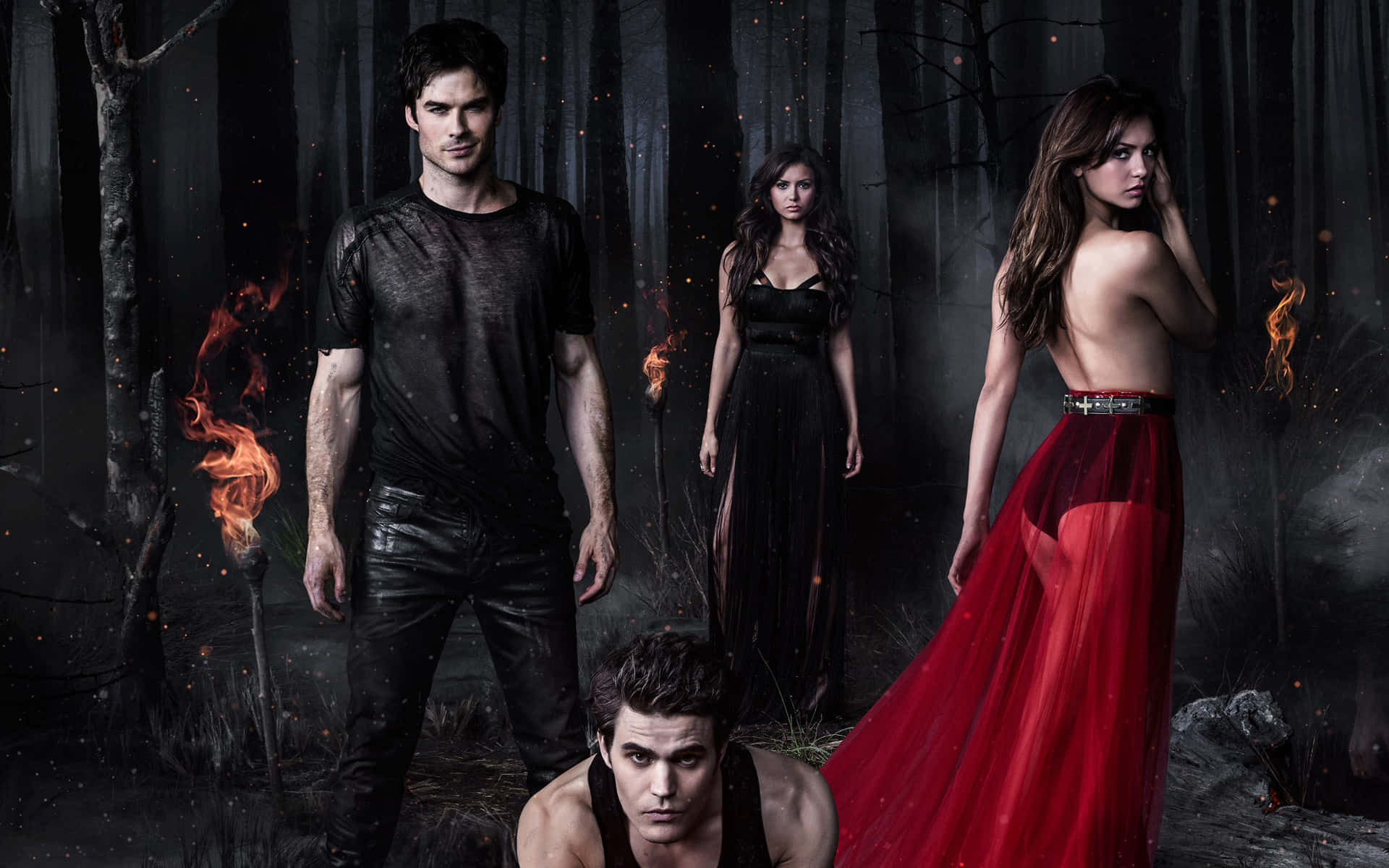 Vampire Diaries Desktop 桌布 壁紙 — 四個吸血鬼站在黑暗的森林中，周圍有閃爍的火焰，一個女人穿著飄逸的紅色連衣裙。
