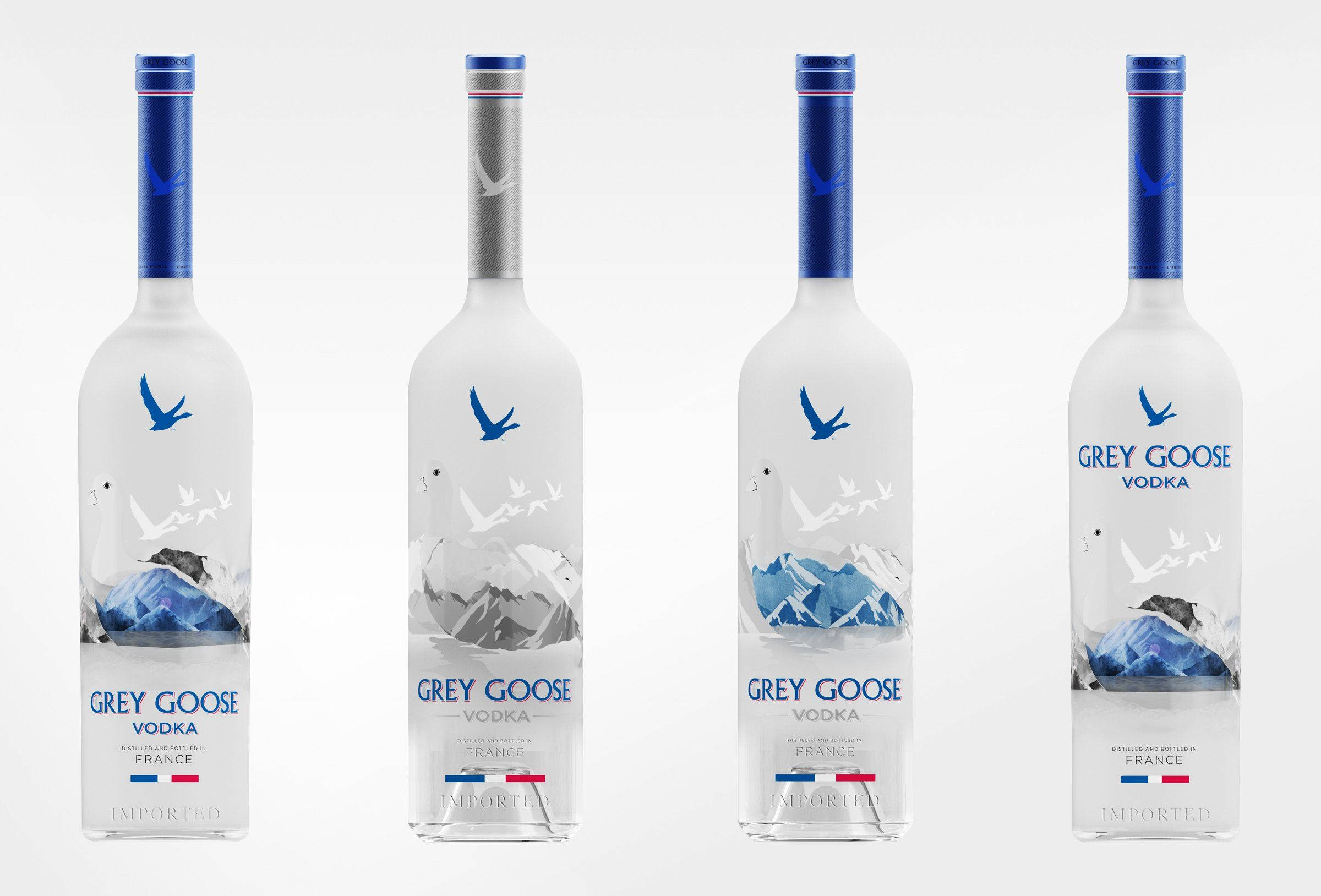 品牌 桌布 壁紙 — 四個帶有藍色蓋子和山鵝圖案的 Grey Goose 伏特加酒瓶，在純白色背景前排列成一排。