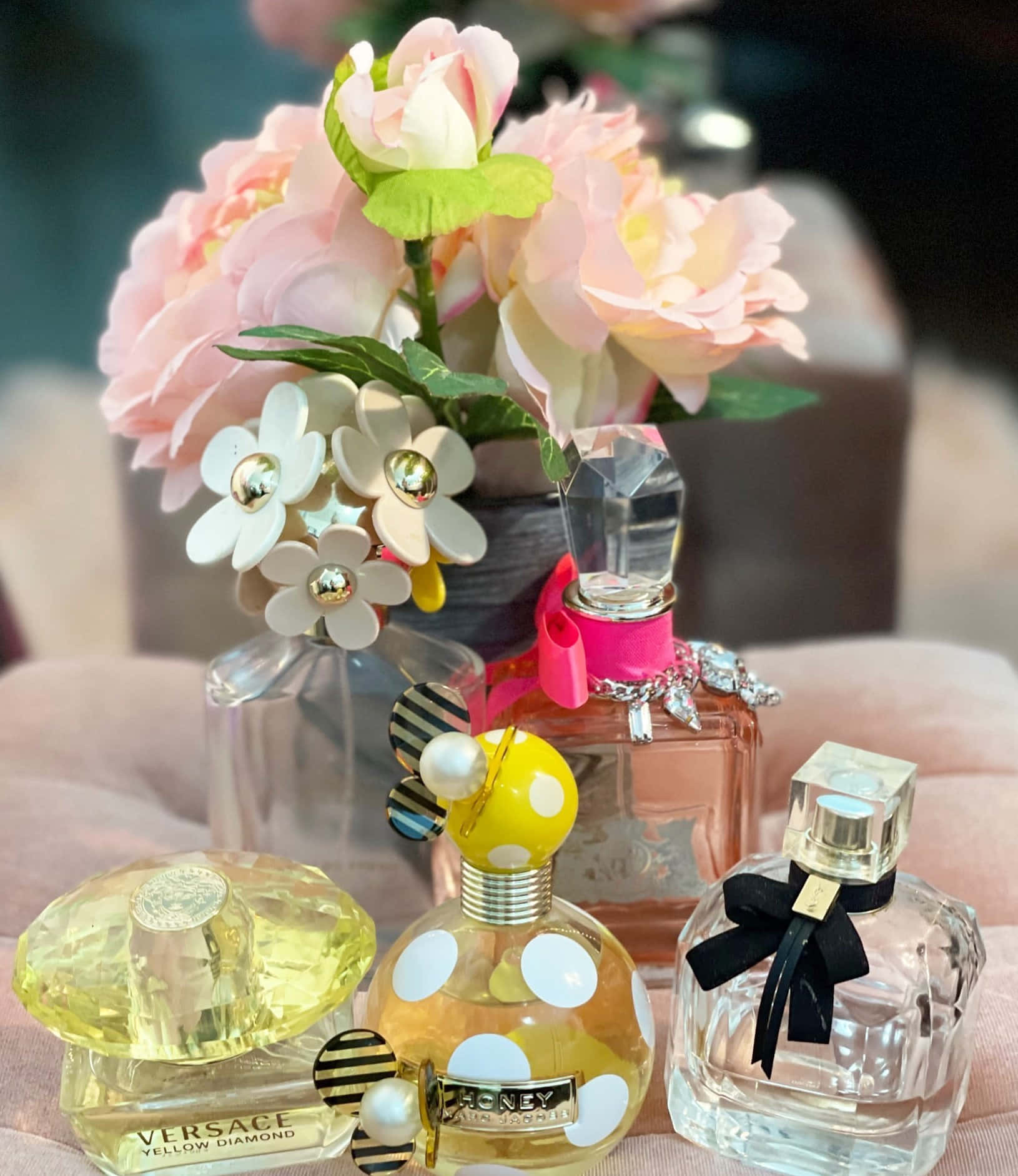 Spring Perfume 桌布 壁紙 — 四個彩色香水瓶排列在柔軟的粉紅色表面上，旁邊是一束粉紅色和白色的花。