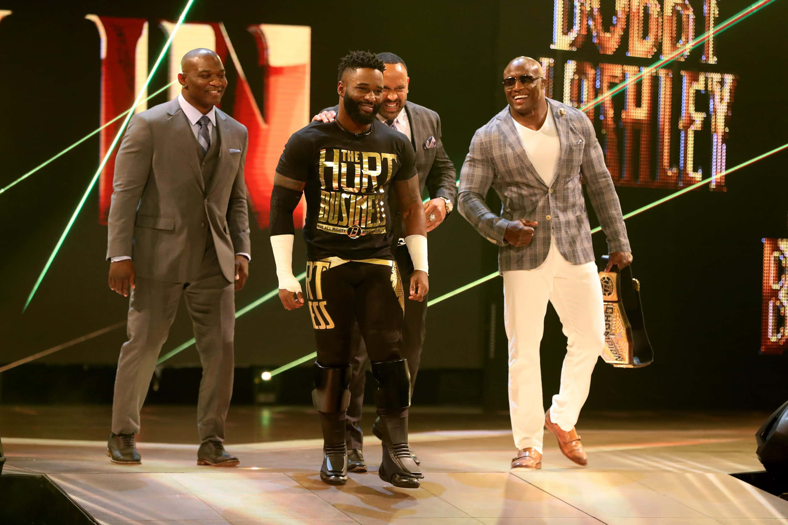 WWE 桌布 壁紙 — 四個微笑的男人自信地走在一個燈光明亮的舞台上，身後有霓虹燈和一個巨大的「DUBBIE HUFFLEY」標誌。