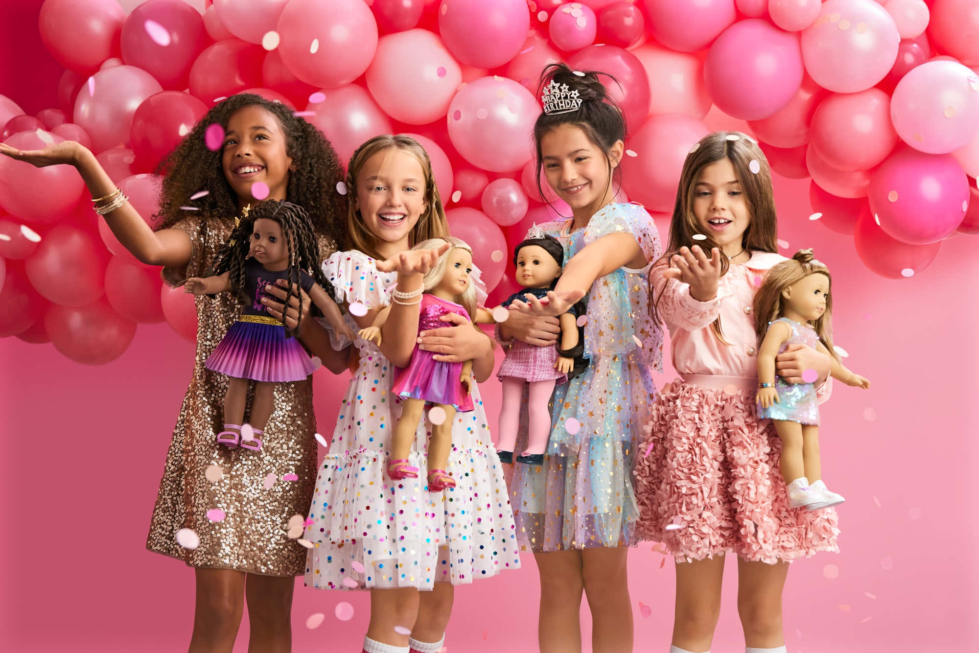 american girl 桌布 壁紙 — 四個快樂的女孩穿著色彩繽紛的裙子，在充滿活力的粉紅色氣球背景和飄落的五彩紙屑中，與美國女孩娃娃合影。