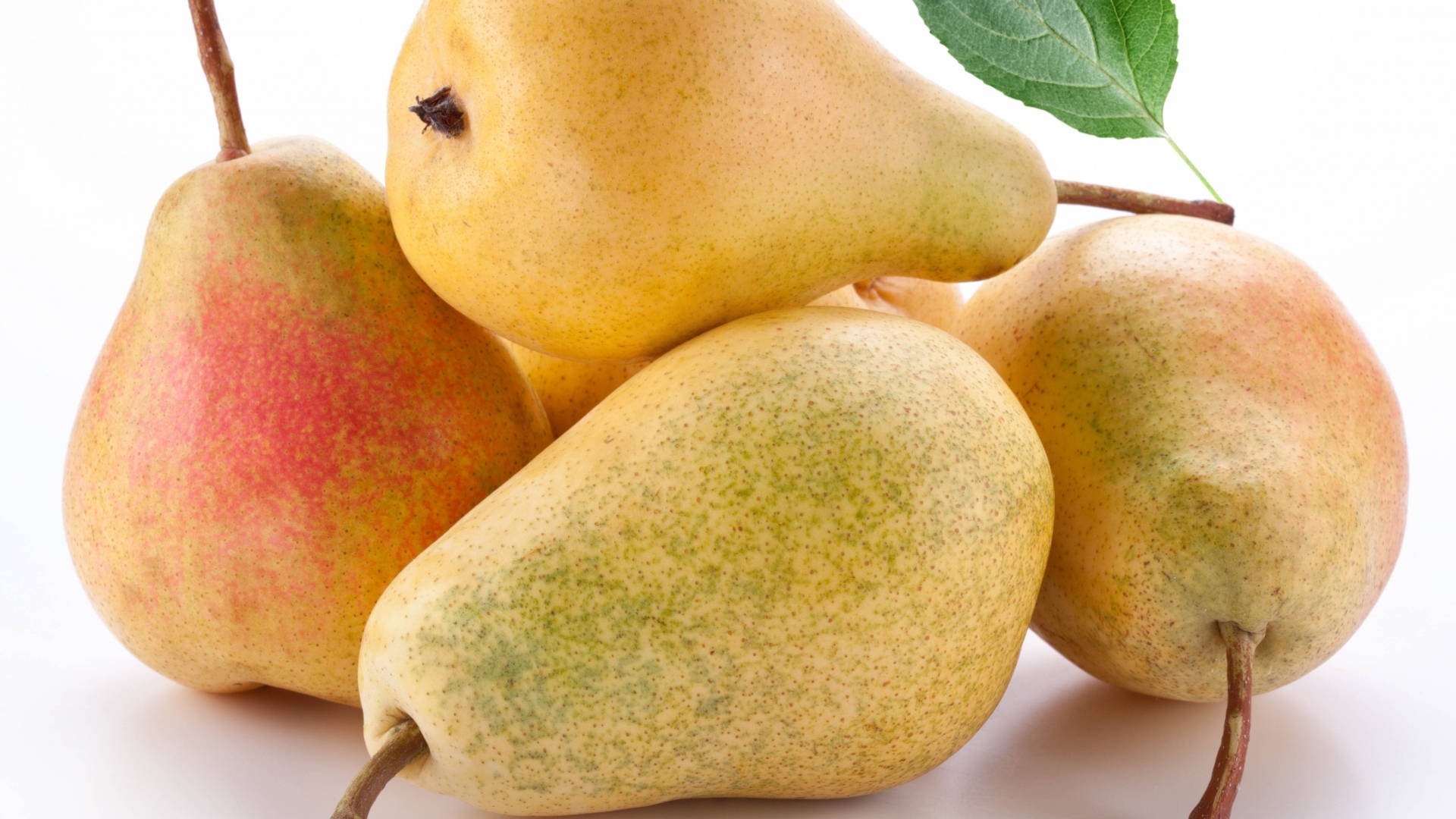 Fruits 桌布 壁紙 — 四個成熟的梨子帶有紅色暈彩和綠色斑點，放在白色表面上，附有一片葉子。