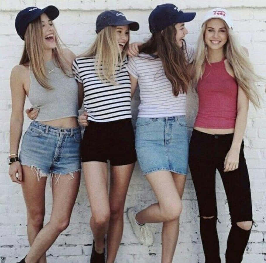 selfie 桌布 壁紙 — 四個戴著帽子、穿著休閒服裝的年輕女子笑著靠在一面白色磚牆上。
