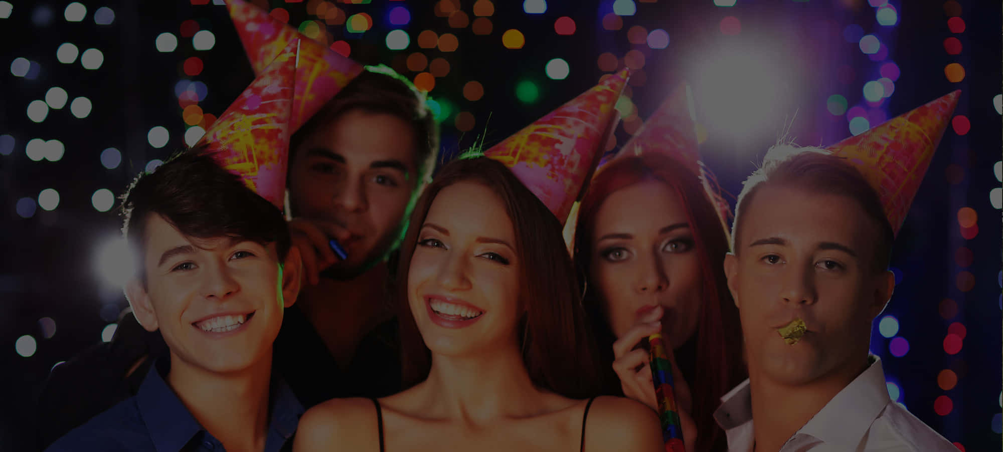 Birthday Party 桌布 壁紙 — 四個戴著派對帽的年輕成年人微笑慶祝，背景是色彩繽紛的散景燈光。