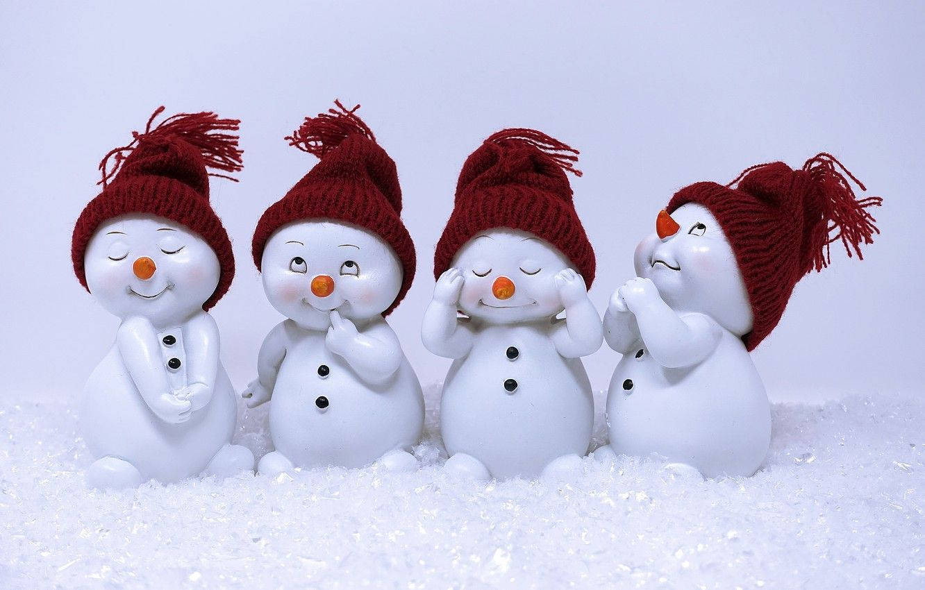 Cute Snowman 桌布 壁紙 — 四個戴著紅色針織帽的快樂雪人公仔一起坐在雪地上，表情愉快。