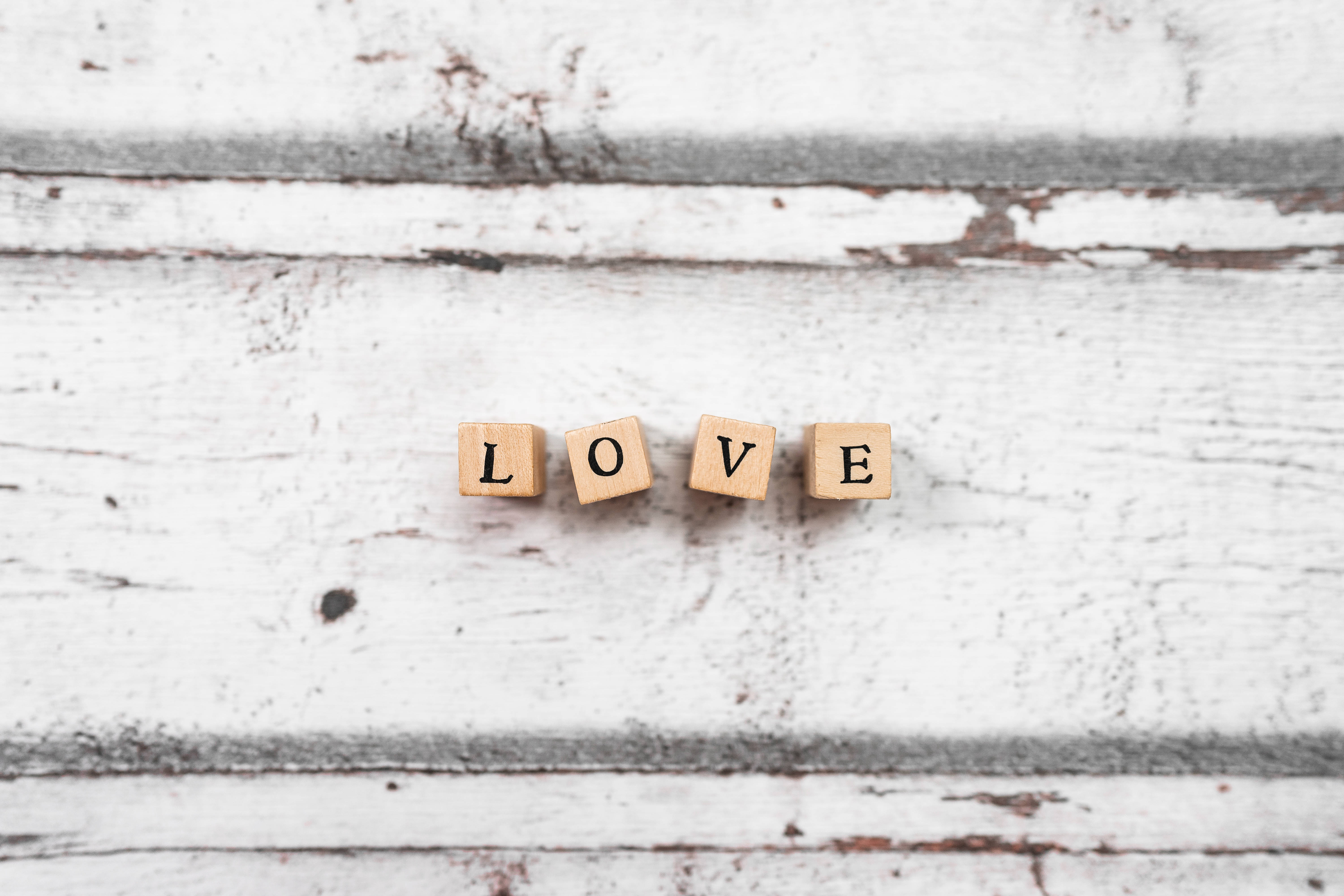 愛情桌面 桌布 壁紙 — 四個拼出 LOVE 的木塊放置在一個磨損、油漆剝落的白色木質表面上。