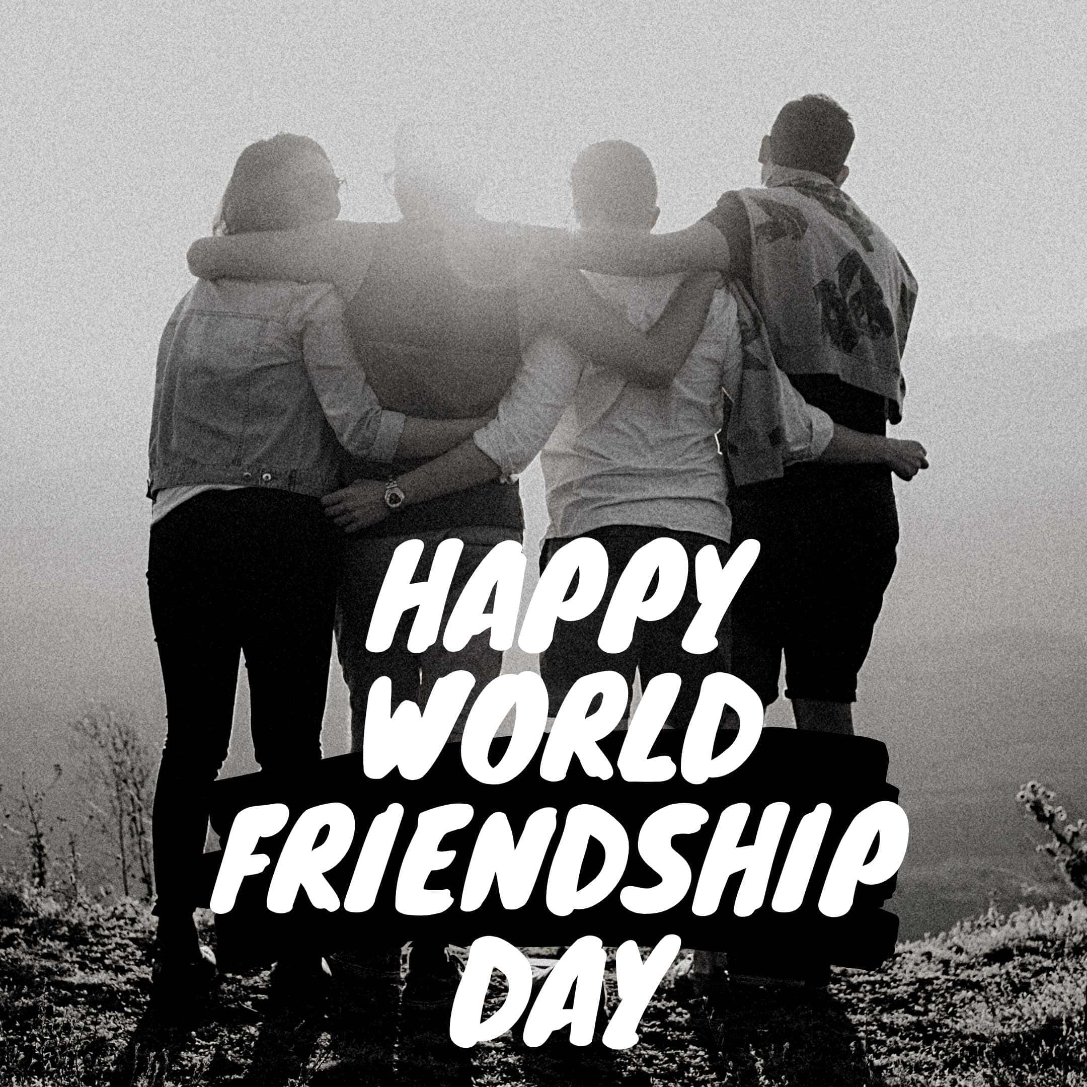 Friendship Day 桌布 壁紙 — 四個朋友在霧氣瀰漫的山頂上圍成一個圓圈擁抱，粗體文字宣告著世界友誼日快樂。