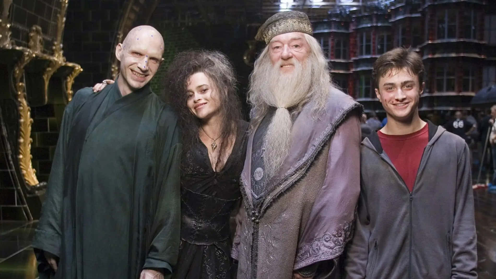 The Hogwarts Professors 桌布 壁紙 — 四個標誌性的哈利波特角色在一個華麗宏偉、帶有金色點綴和深色石牆的大廳中一起擺姿勢。
