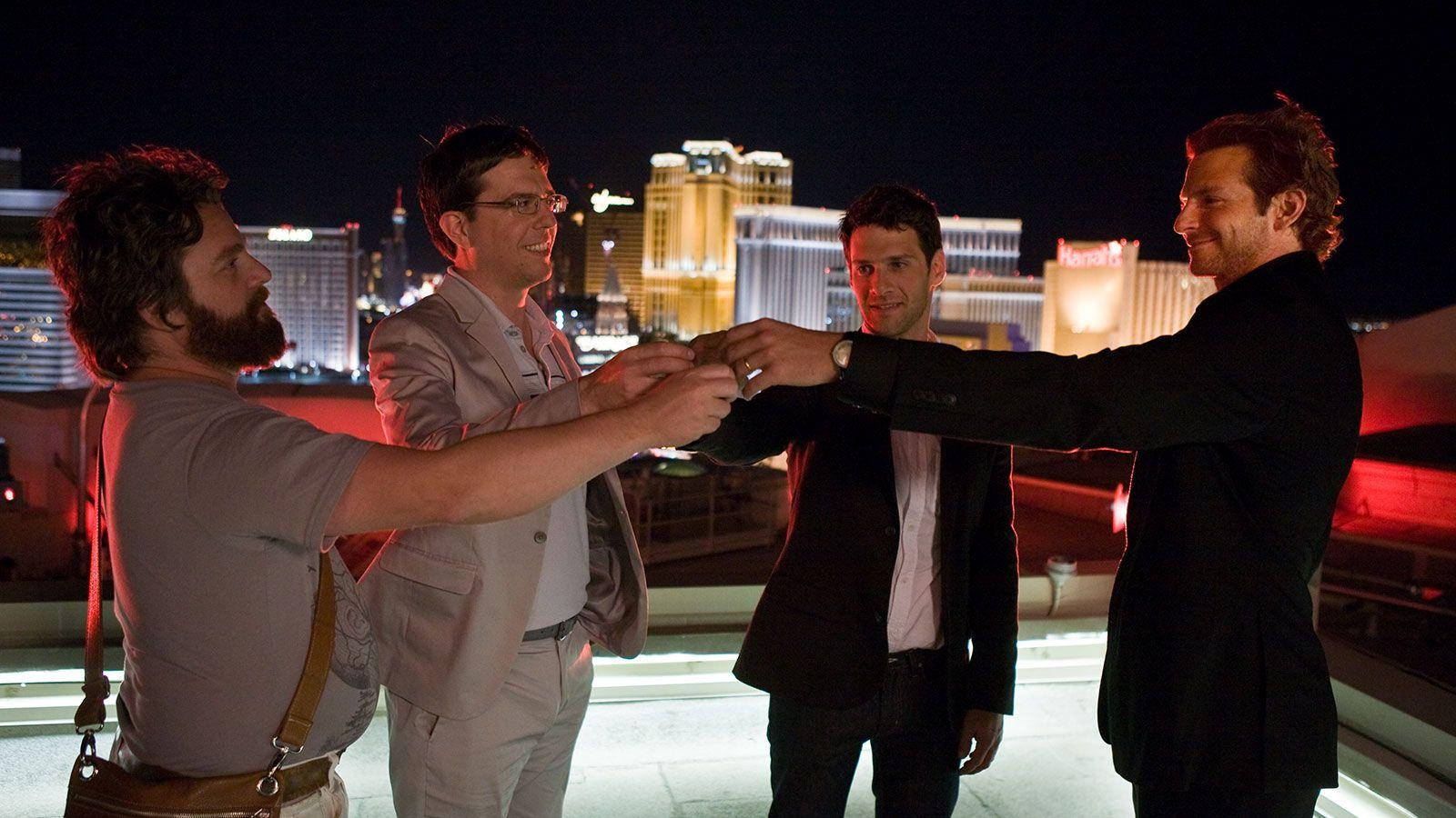 the hangover 桌布 壁紙 — 四個男人在拉斯維加斯的屋頂上，夜晚時分，城市燈光在他們身後閃爍，他們正在舉杯慶祝。