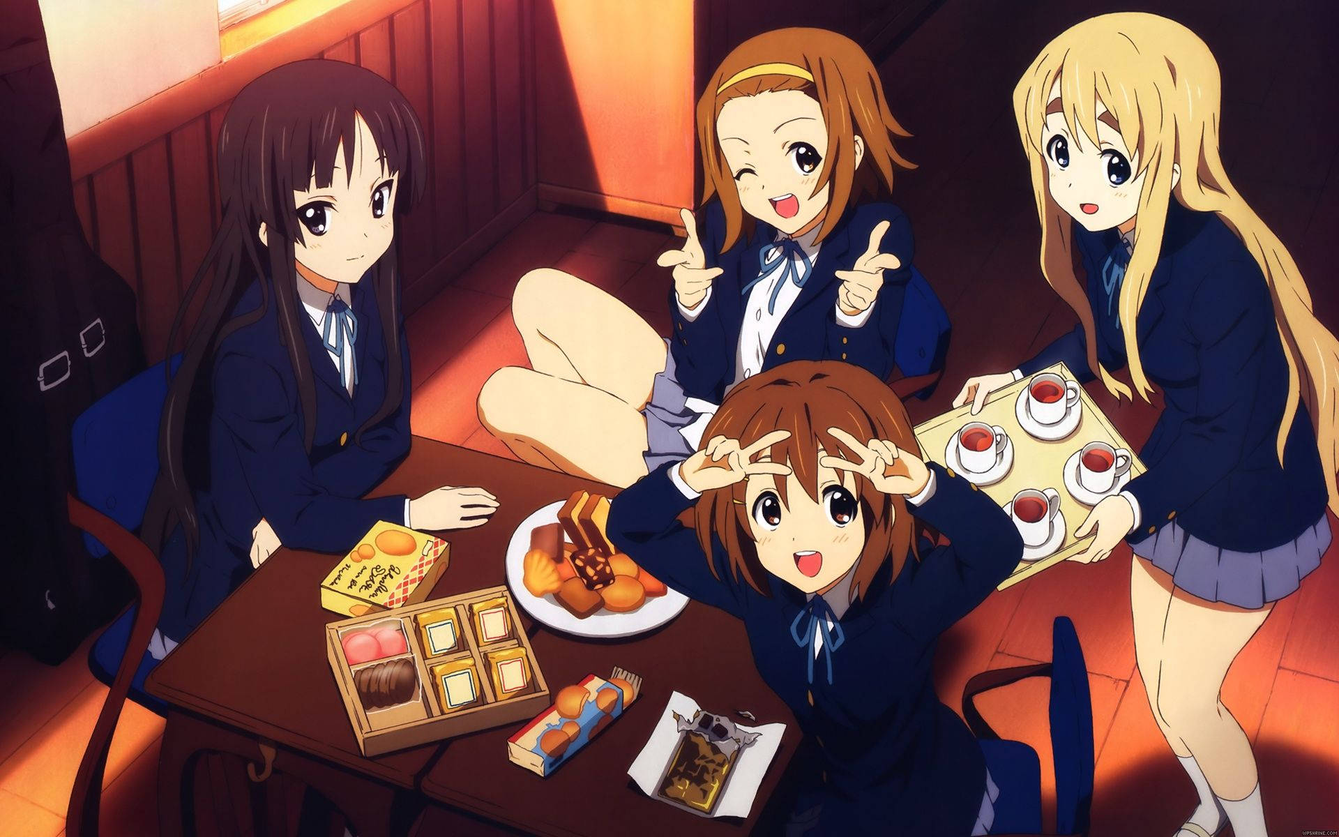 K-on 桌布 壁紙 — 四個穿著校服的動漫女孩聚集在一張擺滿甜點和茶的桌子周圍，房間是木質的，燈光溫暖。